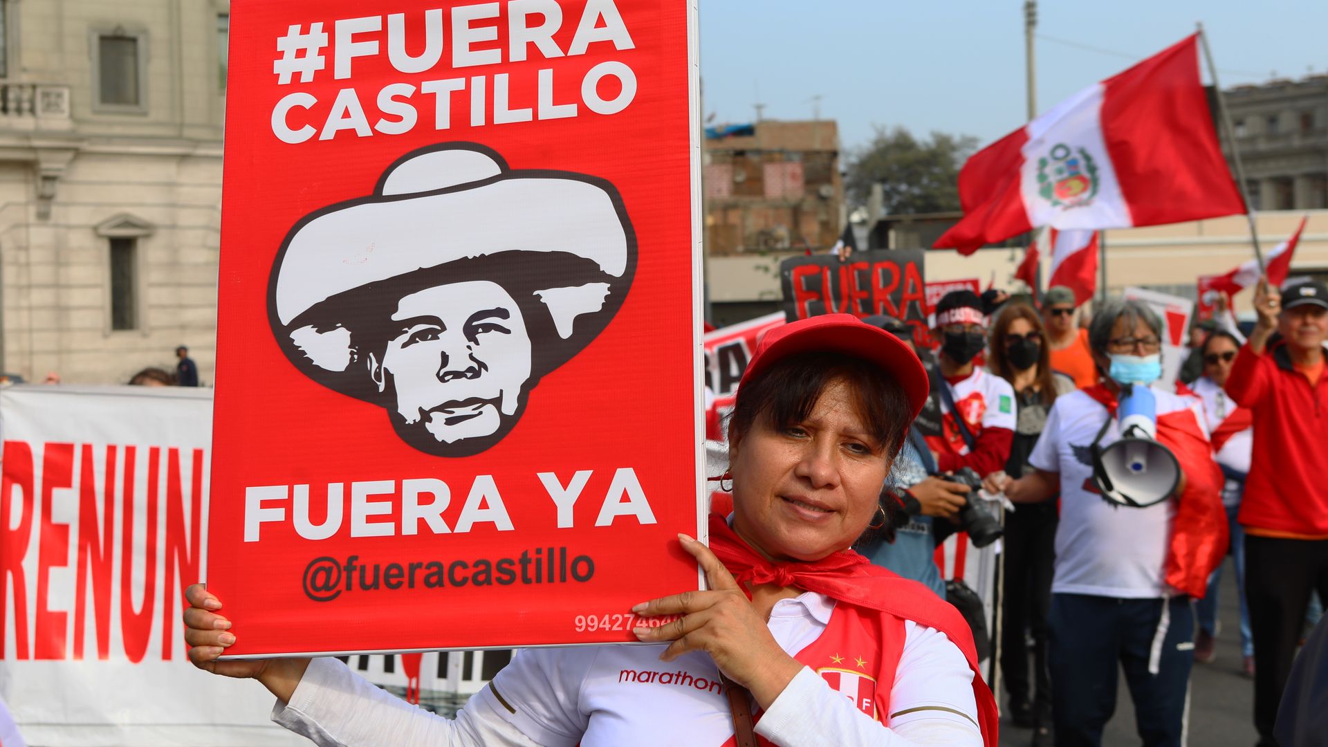 Protesters march through Peru wearing red and white and holding up large signs that say "out Castillo" referencing the embattled president