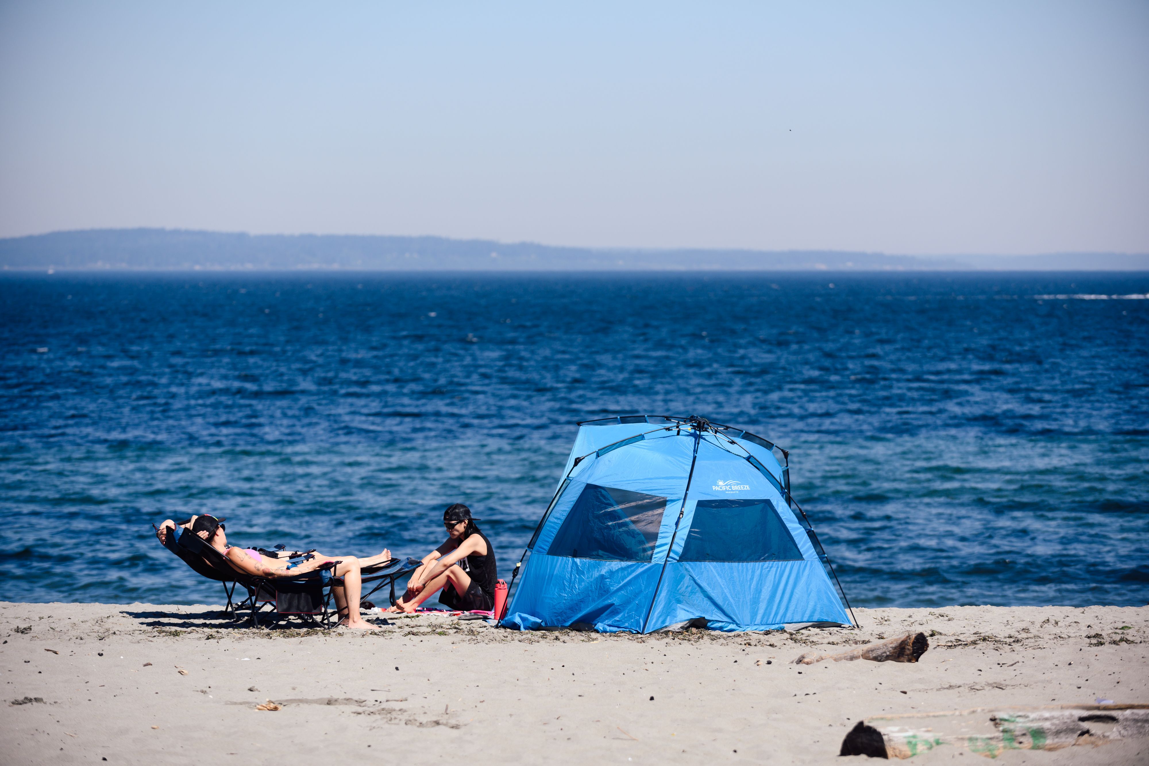 People relax near a tent on Alki Beach