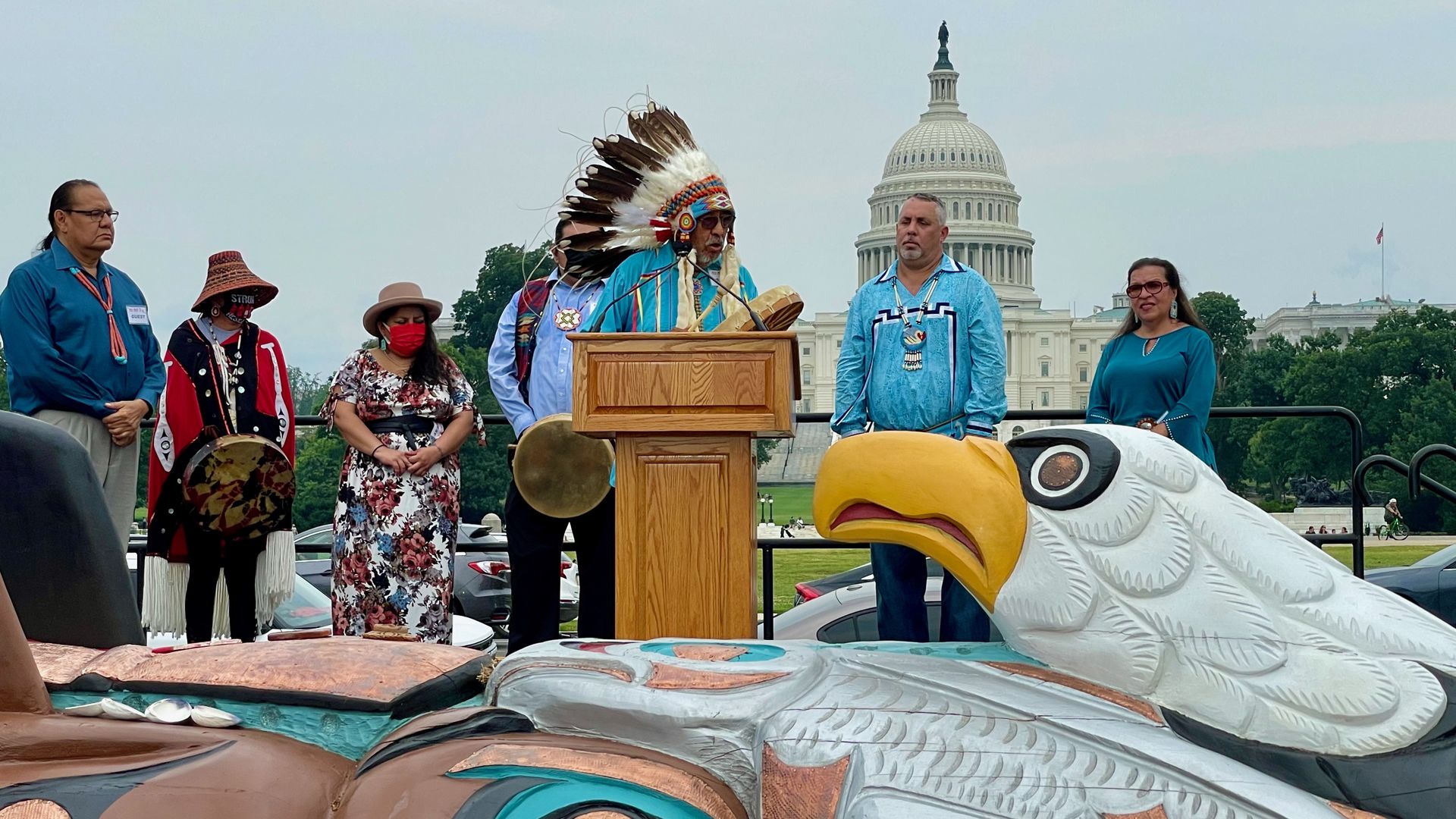 Native Americans are seen singing to welcome a totem pole carved by Lummi Nation carvers erected at the National Mall on Thursday.