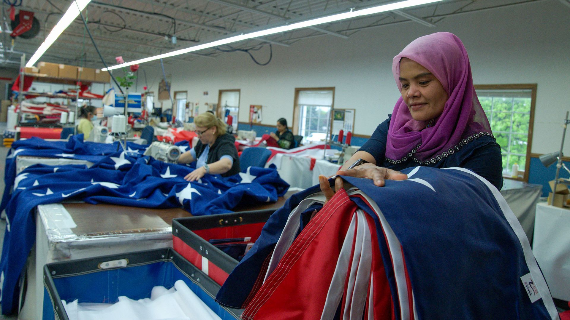 A woman holds a large American flag in her hand