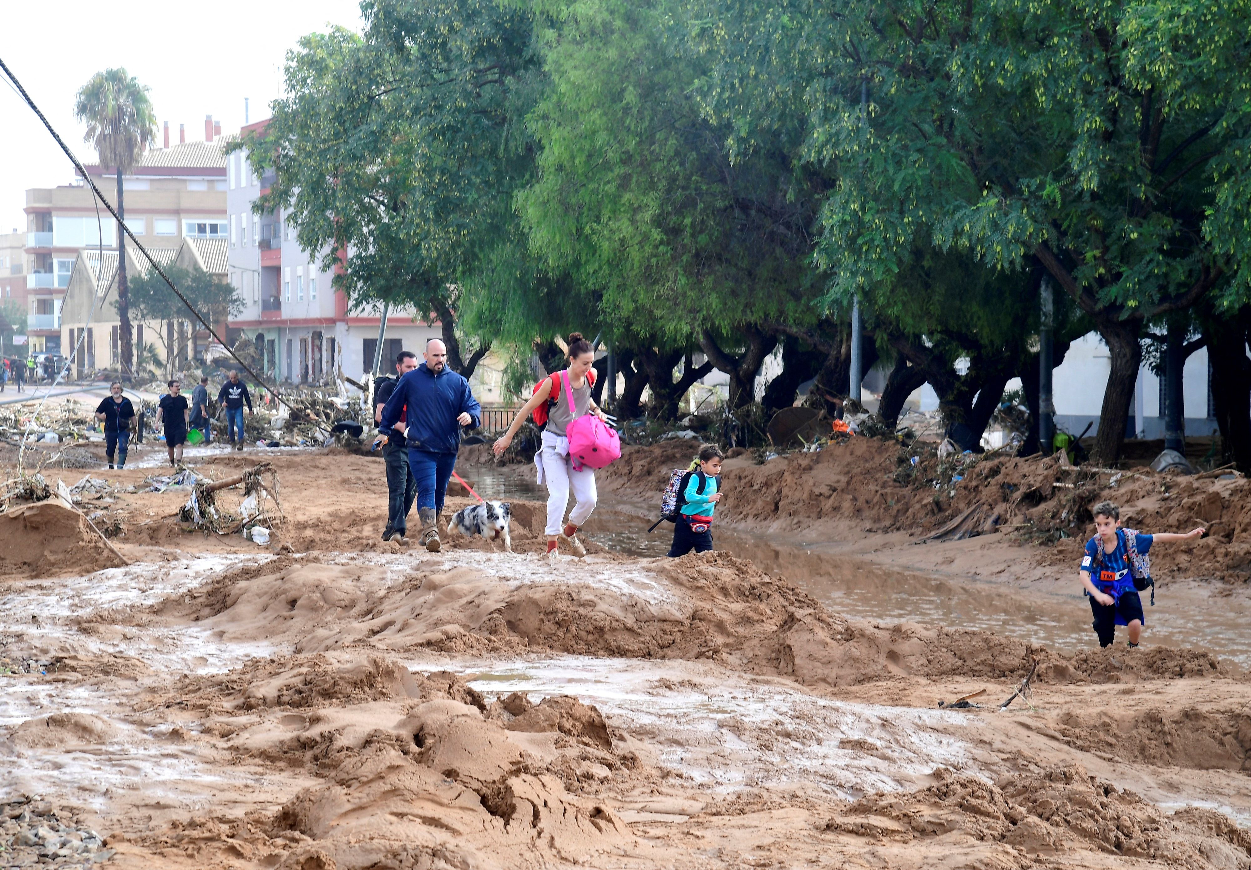 A resident cleans her house next to cars piles due to mudslide in a flooded area in Picanya, near Valencia, eastern Spain, on October 30