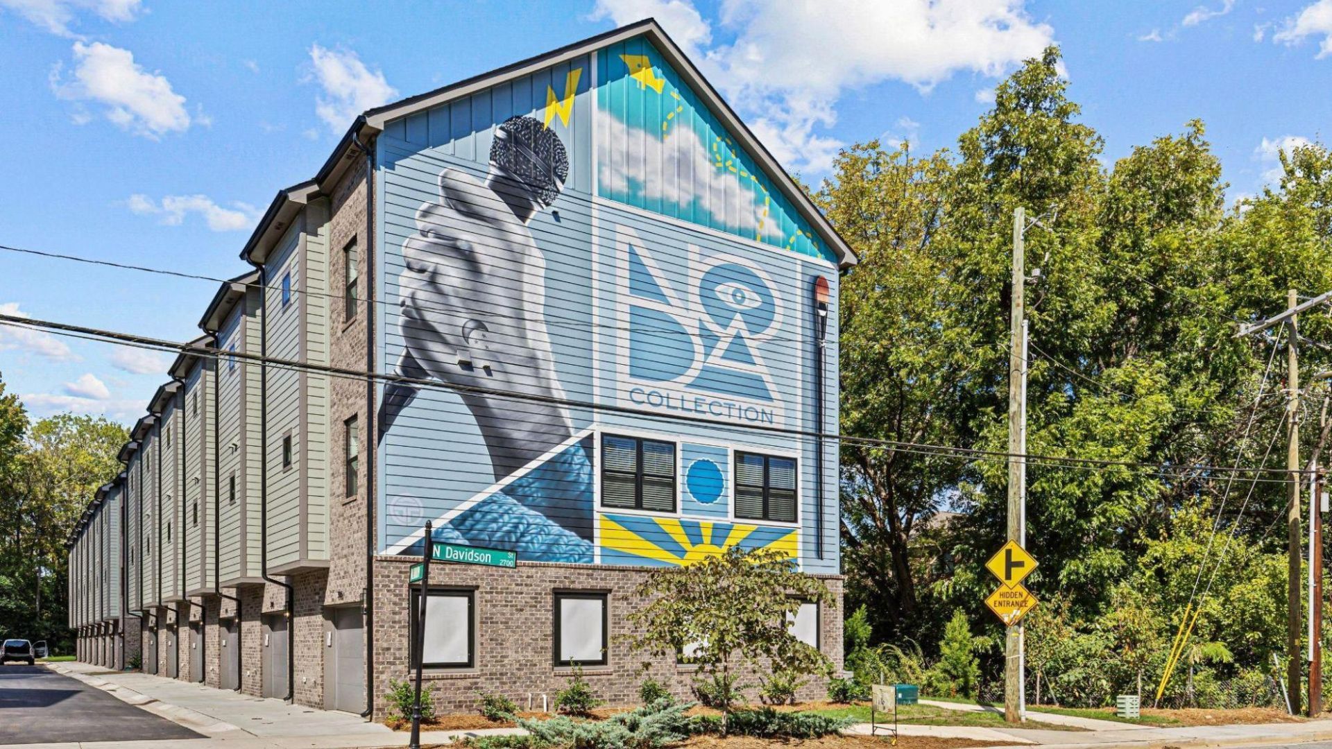The exterior of an apartment building. There is a mural on the side. 