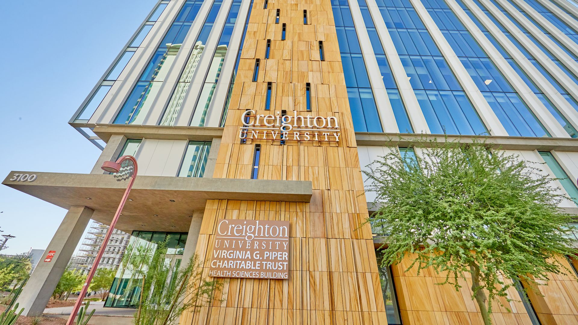 A street-level view looking up at a wood and glass Creighton University building.