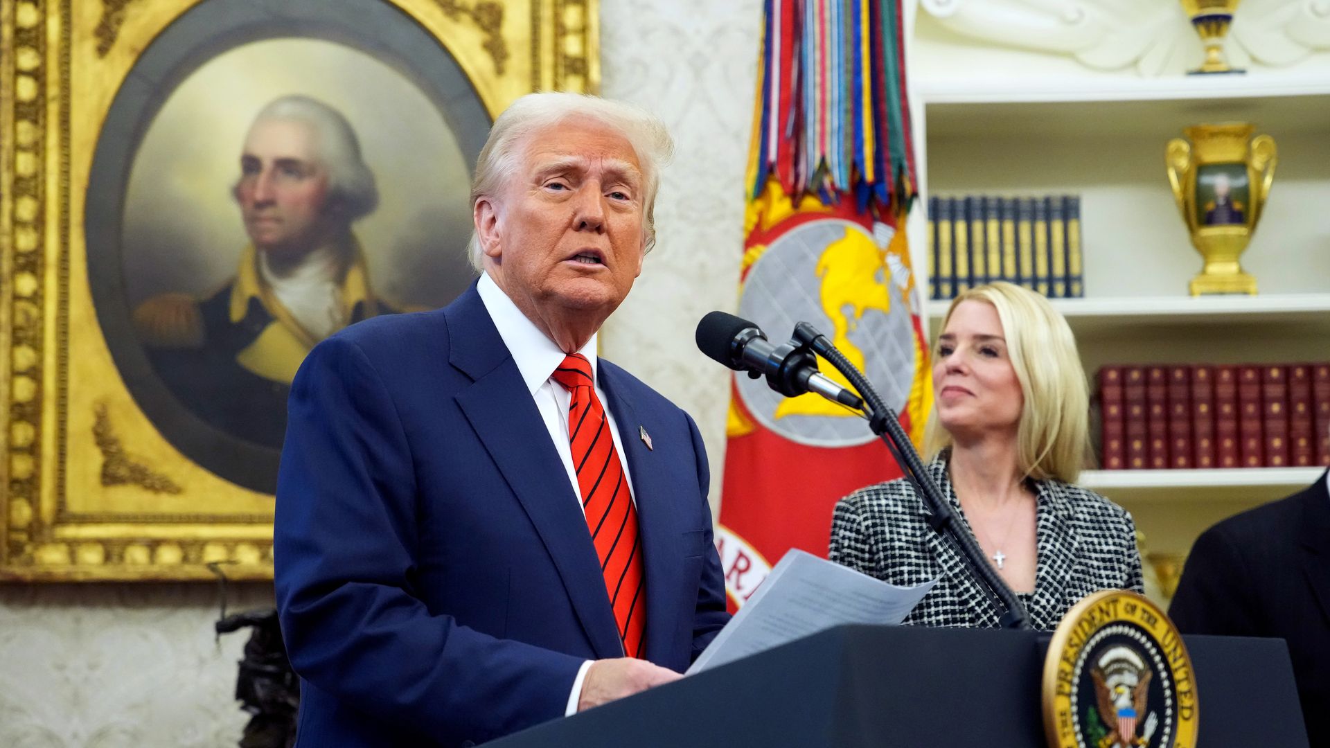 President Trump speaks at a podium next to Attorney General Pam Bondi.