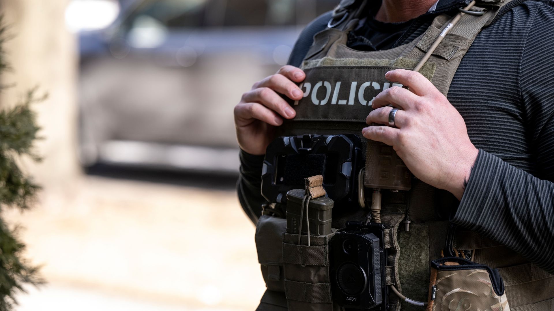 An officer stands wearing a police vest. 