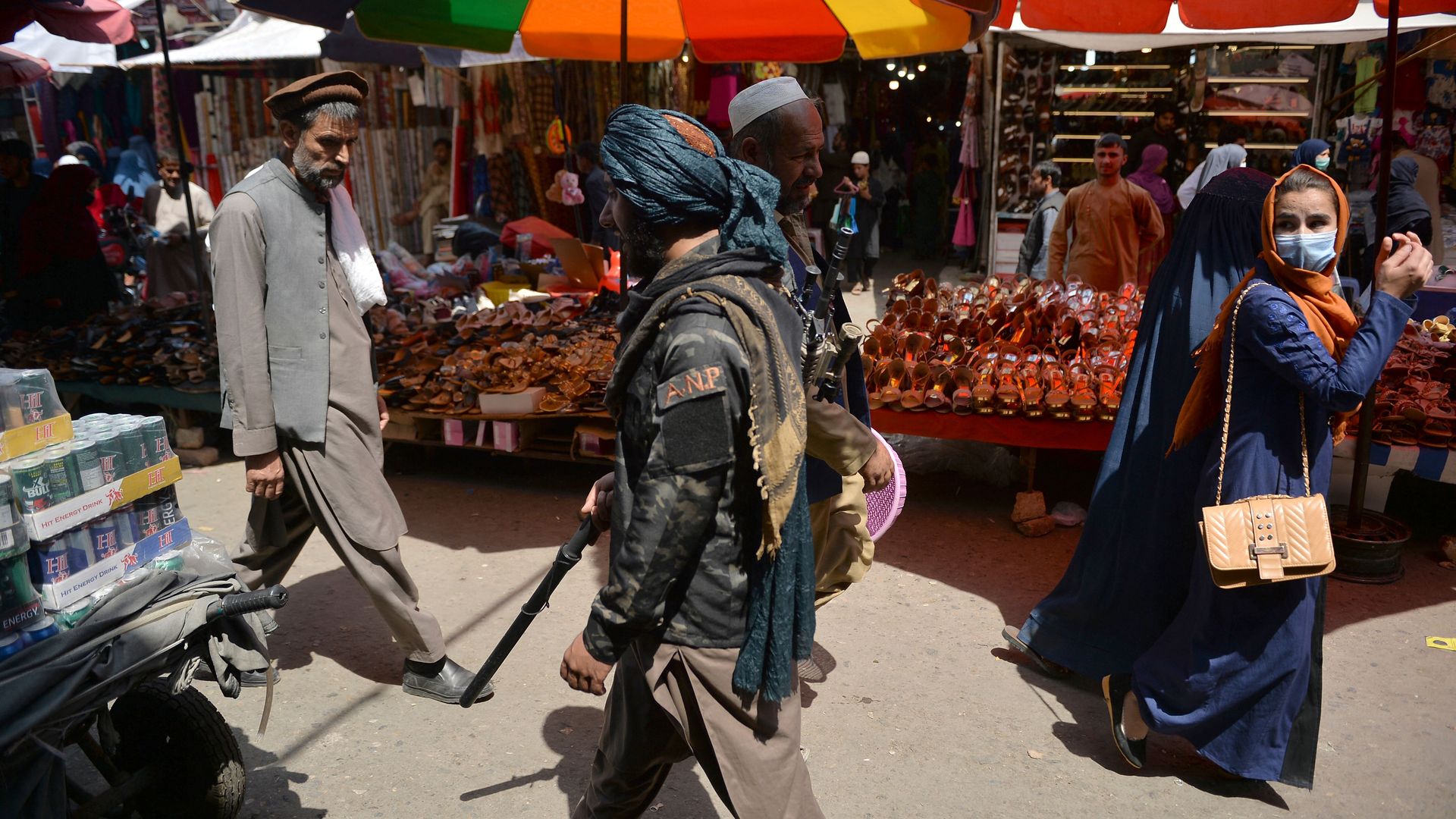 A Taliban fighter (C) walks past shoppers along Mandawi market in Kabul on September 1, 2021