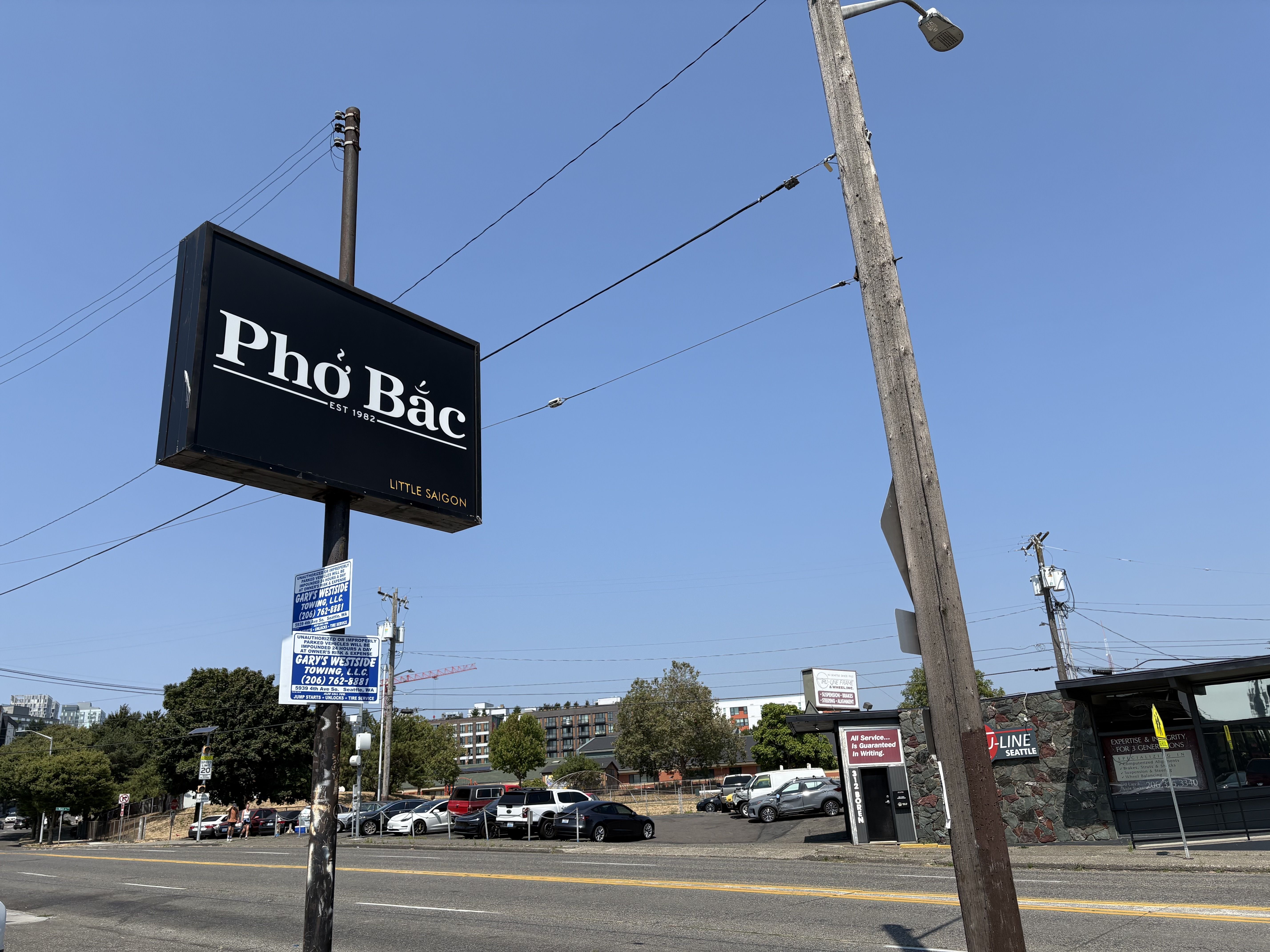 A black sign with white lettering says "Pho Bac" on an urban street. 