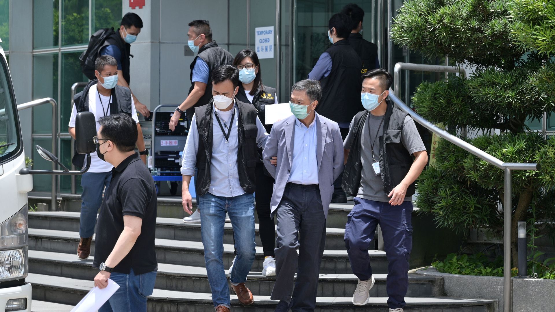  Chief Operations Officer Chow Tat Kuen (front 2nd R) is escorted by police from the Apple Daily newspaper offices before being put into a waiting vehicle in Hong Kong on June 17