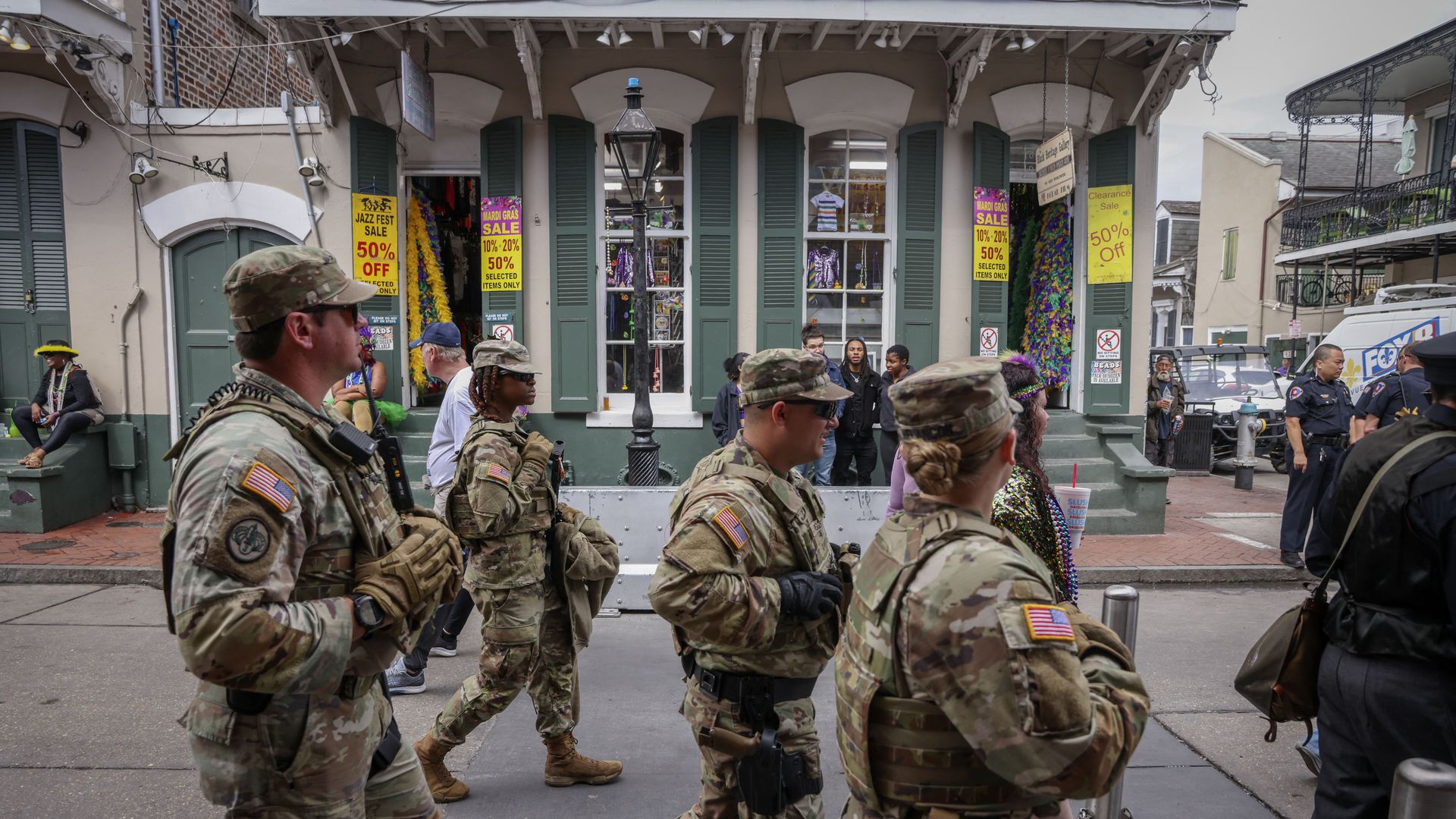Four National Guard troopers, in uniform, walk past a Bourbon Street gift shop.