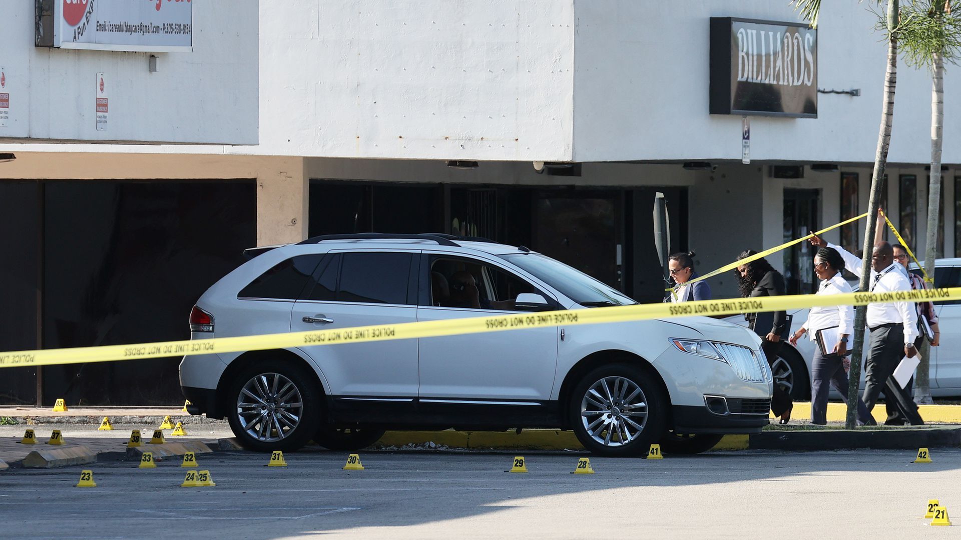 A van involved in a crime scene is behind yellow caution tape, as police investigate.