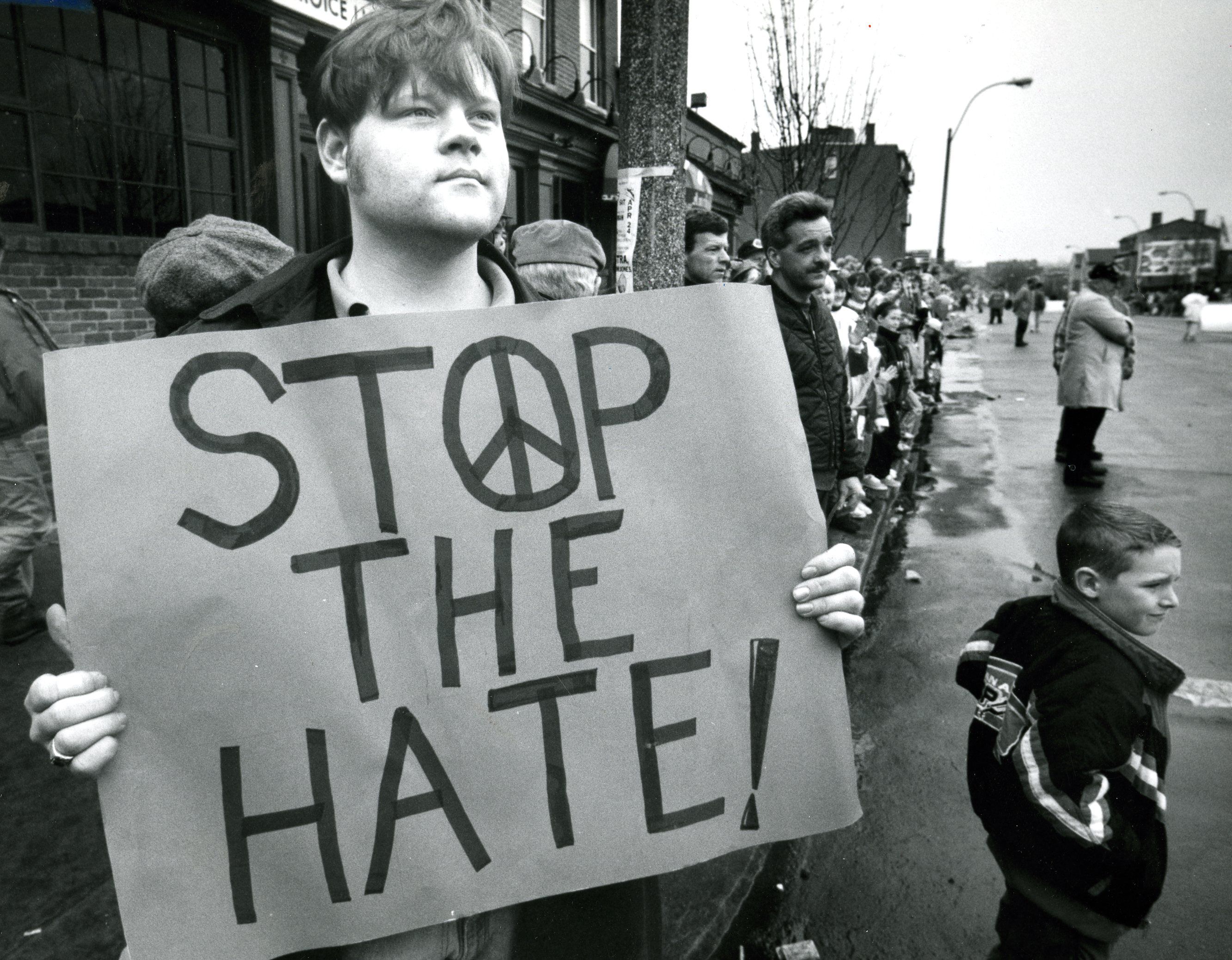A man looks on at the parade, holding a sign that says "Stop the hate!" during the St. Patrick's Day parade in Boston. A group of gay people walked in the parade despite organizers' wishes.