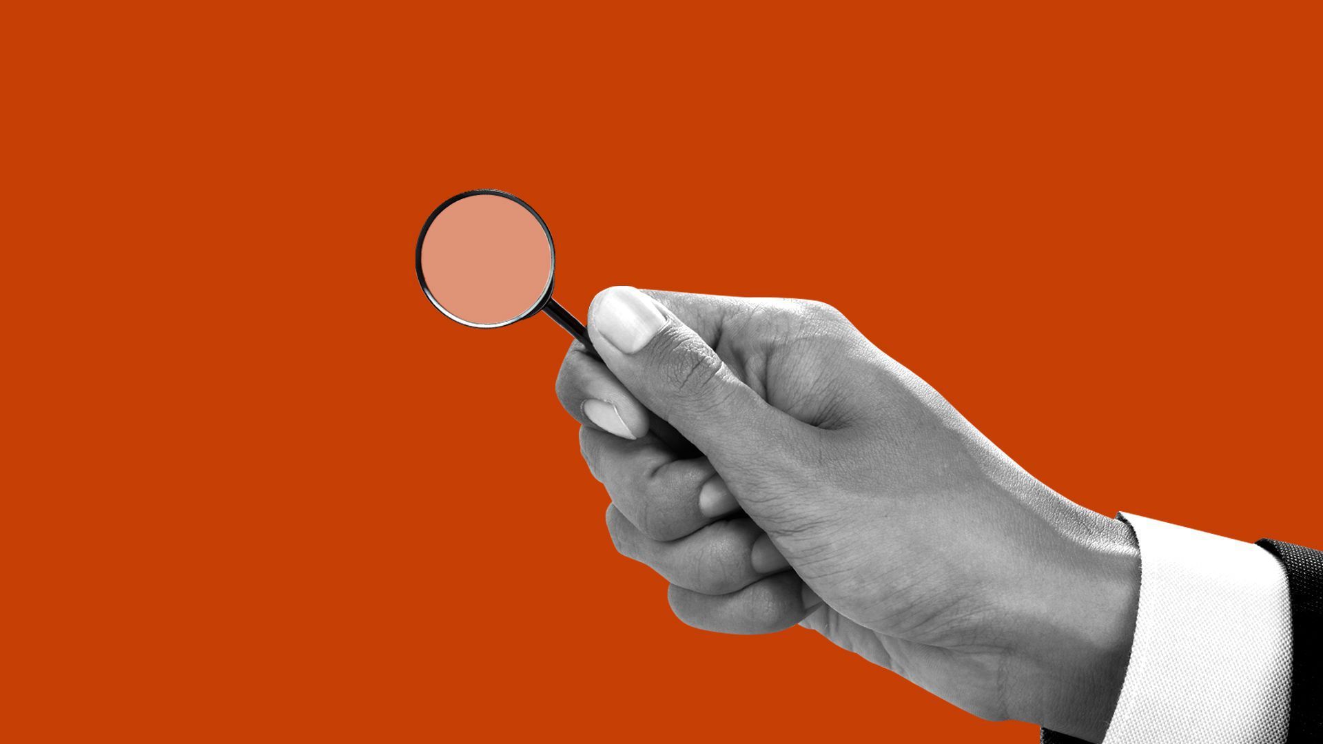 A person wearing a suit holds a small magnifying glass