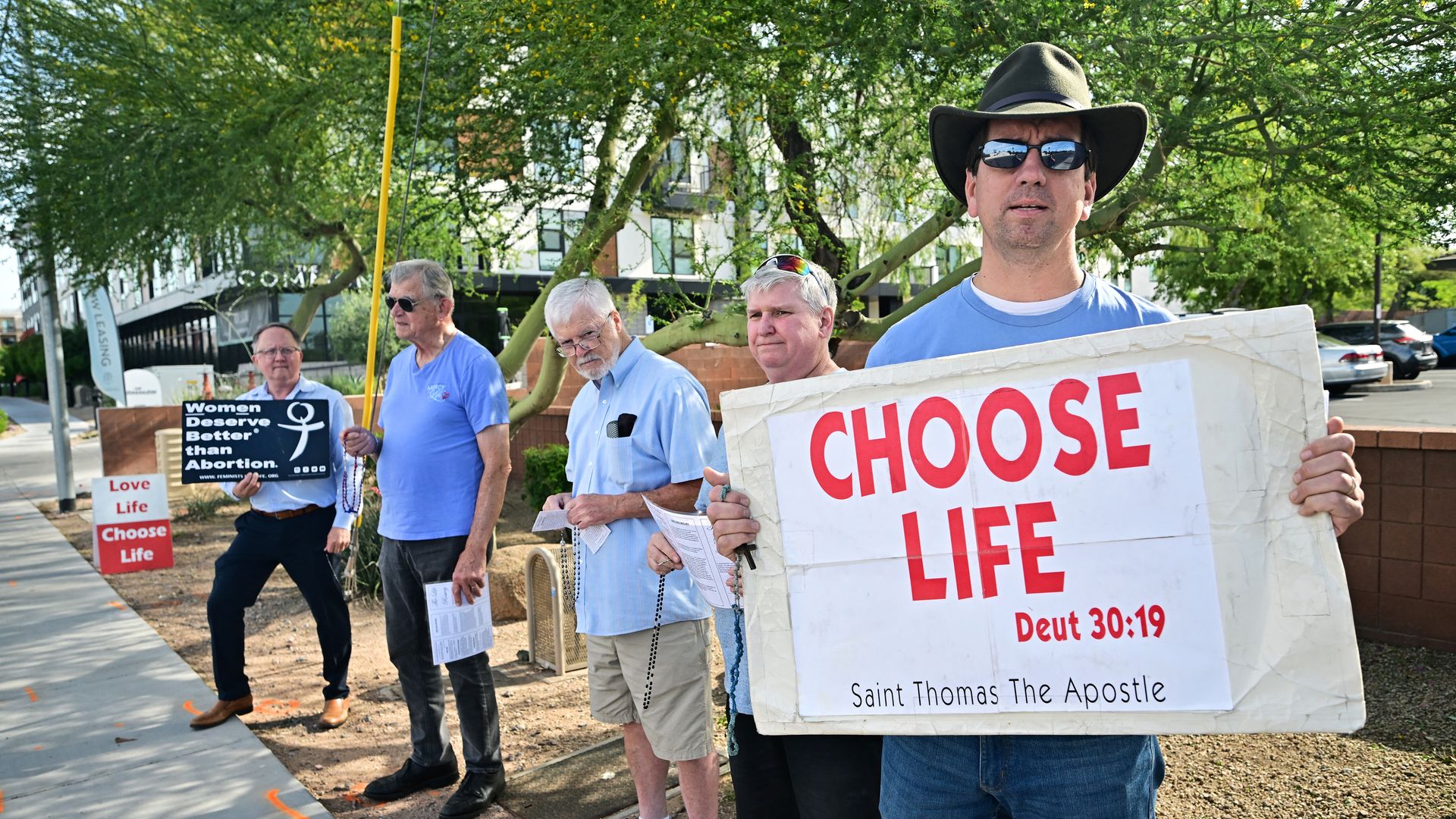 A group of men holding signs that say, "Choose Life."