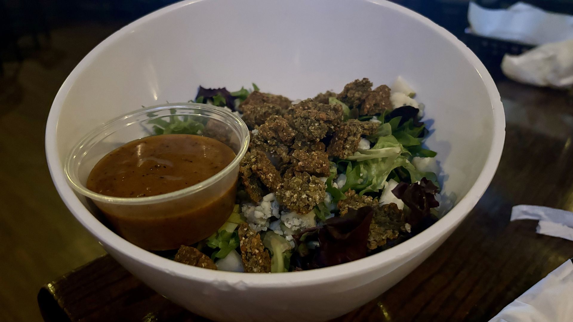A cup of dressing in a salad bowl. 