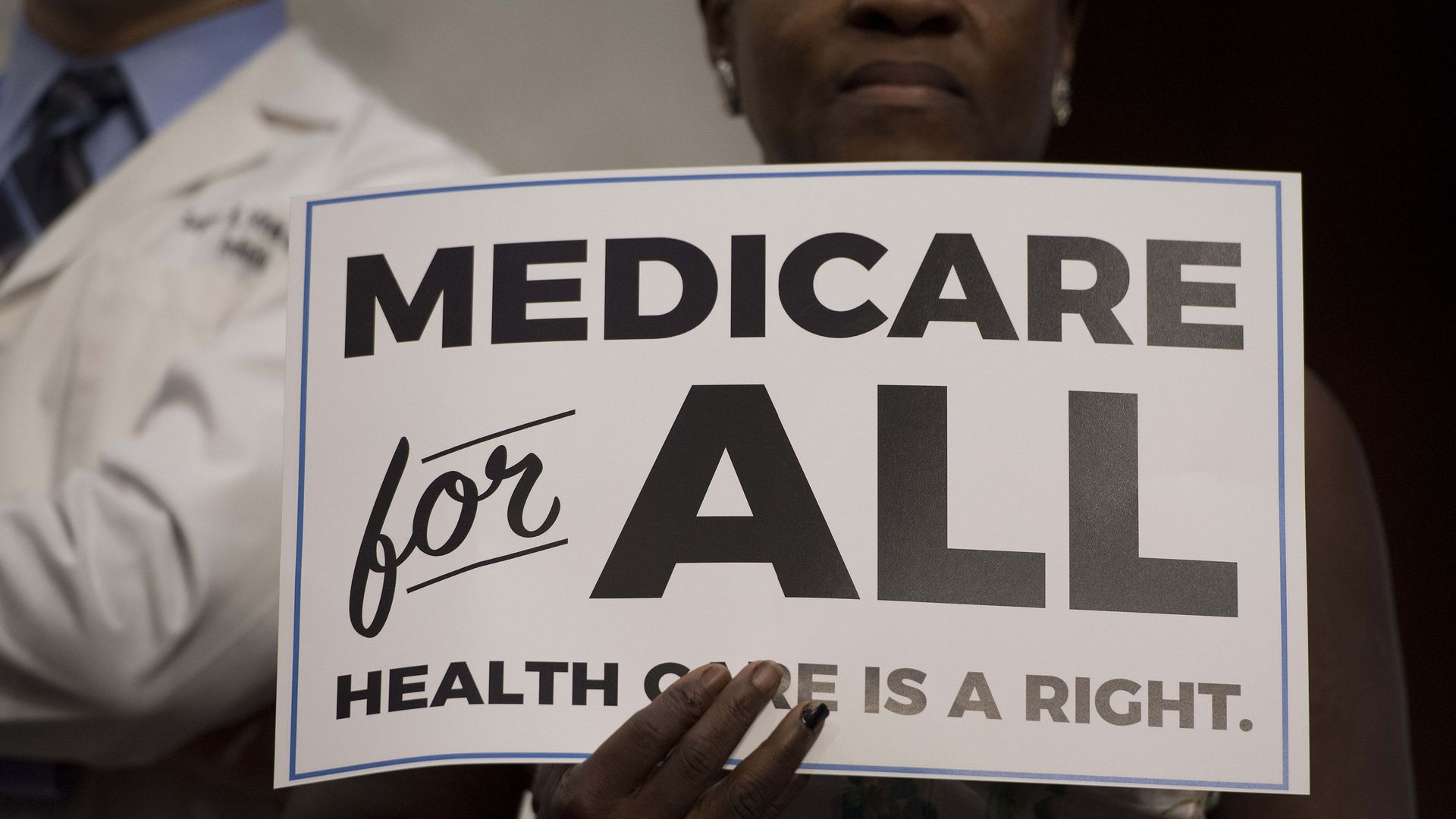 A woman holds up a sign advocating for "Medicare for All" 