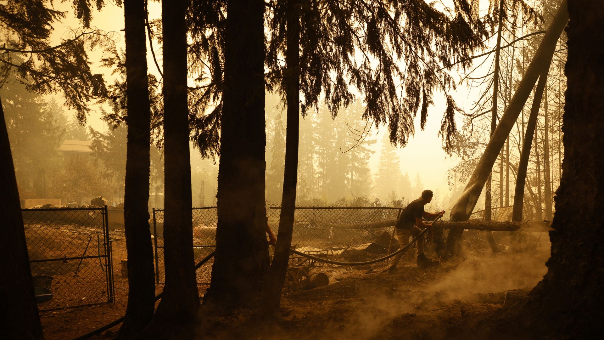 A man sprays water on hot spots during a wildfire in British Columbia during 2023.