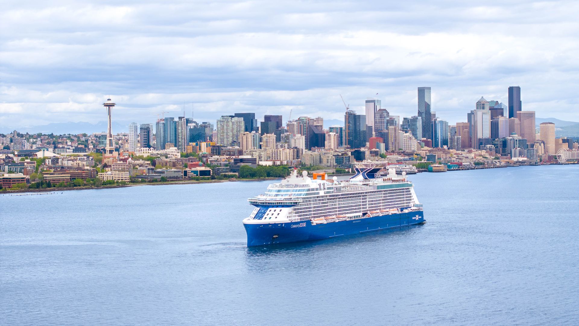 A photo of a cruise ship in Elliott Bay with the Space Needle and skyline in the background.