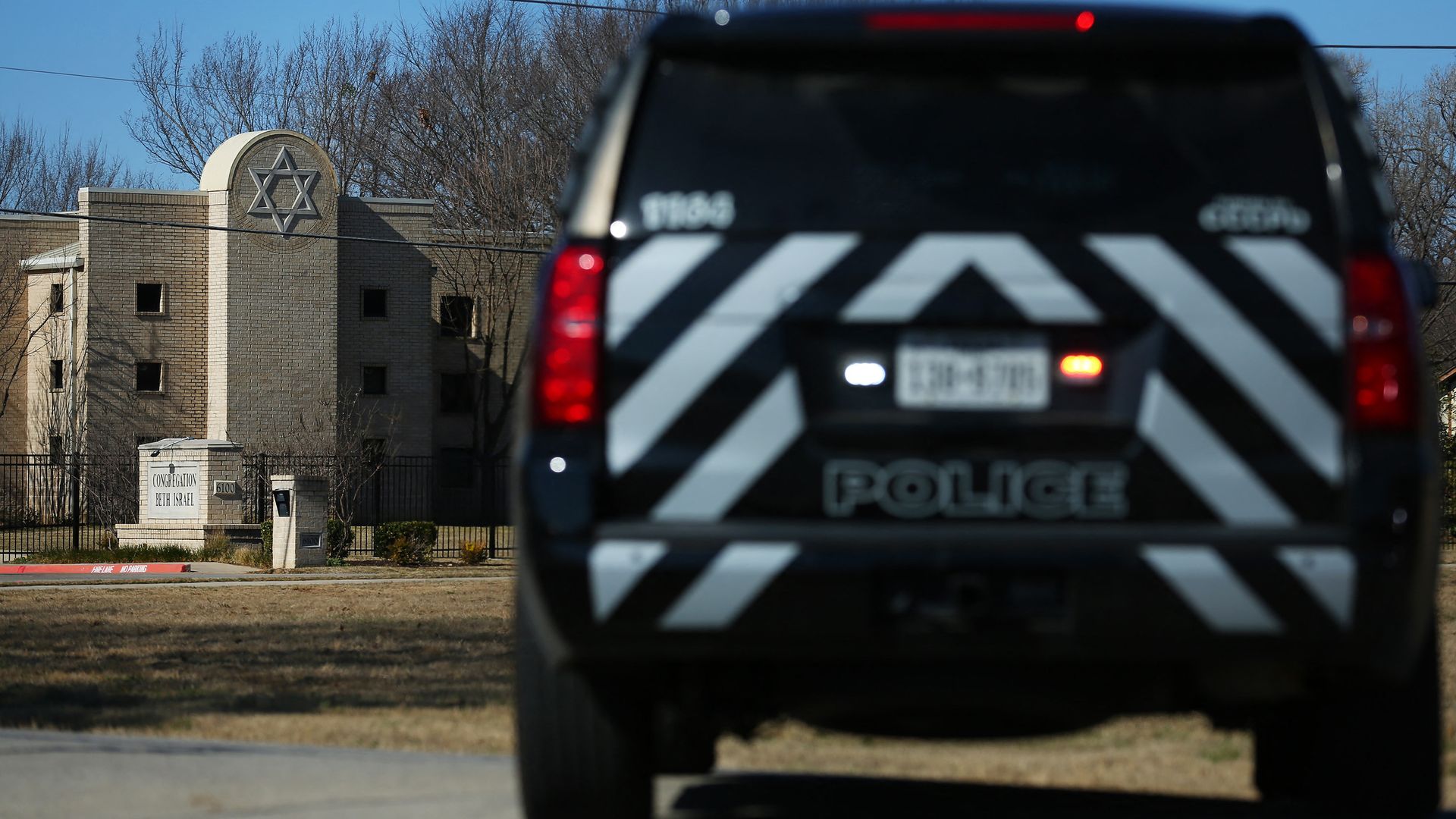 A police vehicle is parked outside a Jewish synagogue. 
