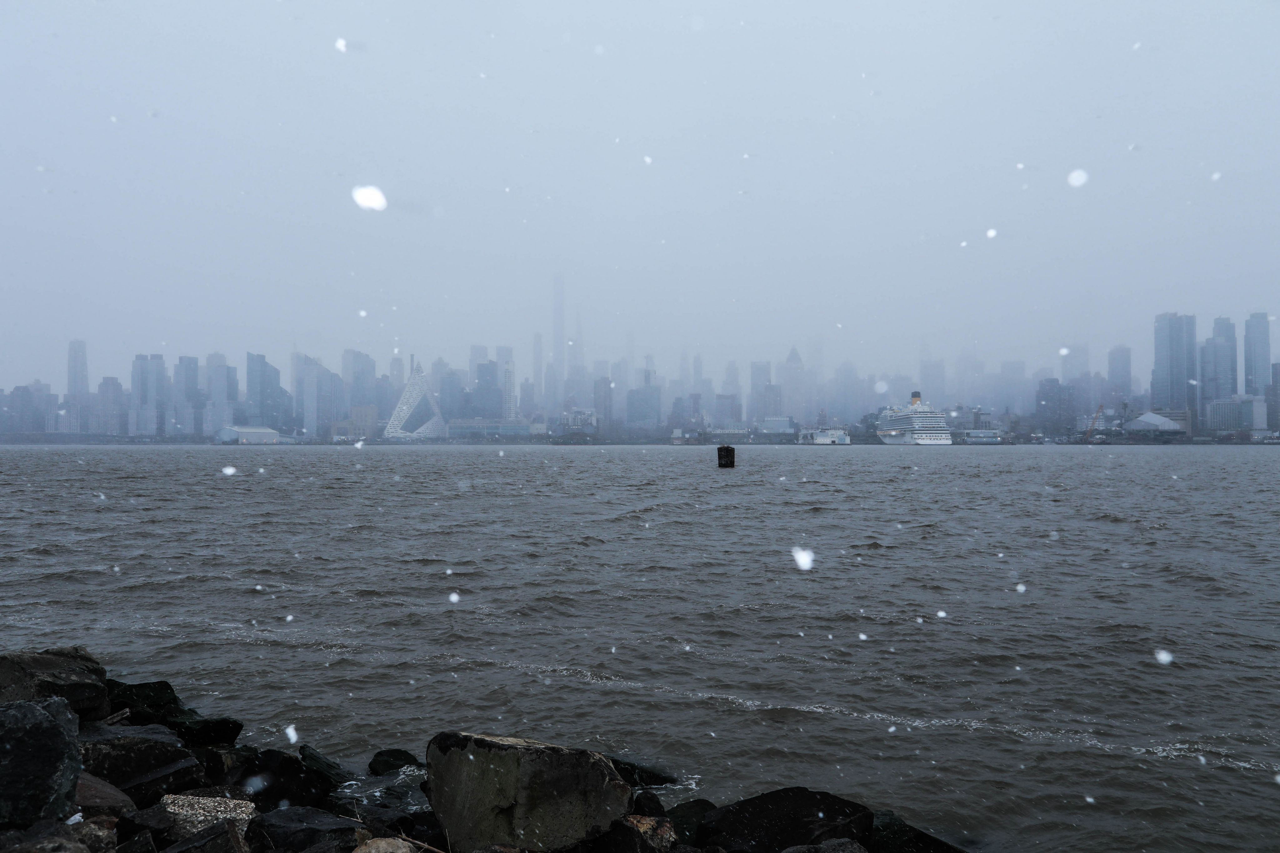 Snow flurries fall as the New York skyline is seen on the background of the Hudson River from Weehawken, New Jersey, on January 6, 2024. Forecasters warned on January 5 that a deluge of snow and wintery conditions could bring travel chaos to the US northeast this weekend, with some 25 million people subject to a storm warning.