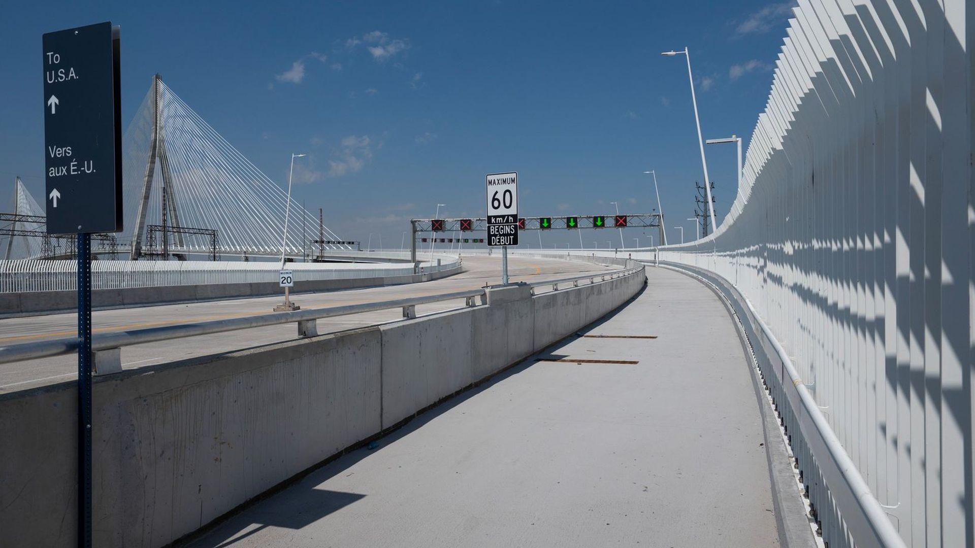 A white pathway is lined with fencing and the rest of the bridge visible in the background. Vehicle lanes can be seen nearby