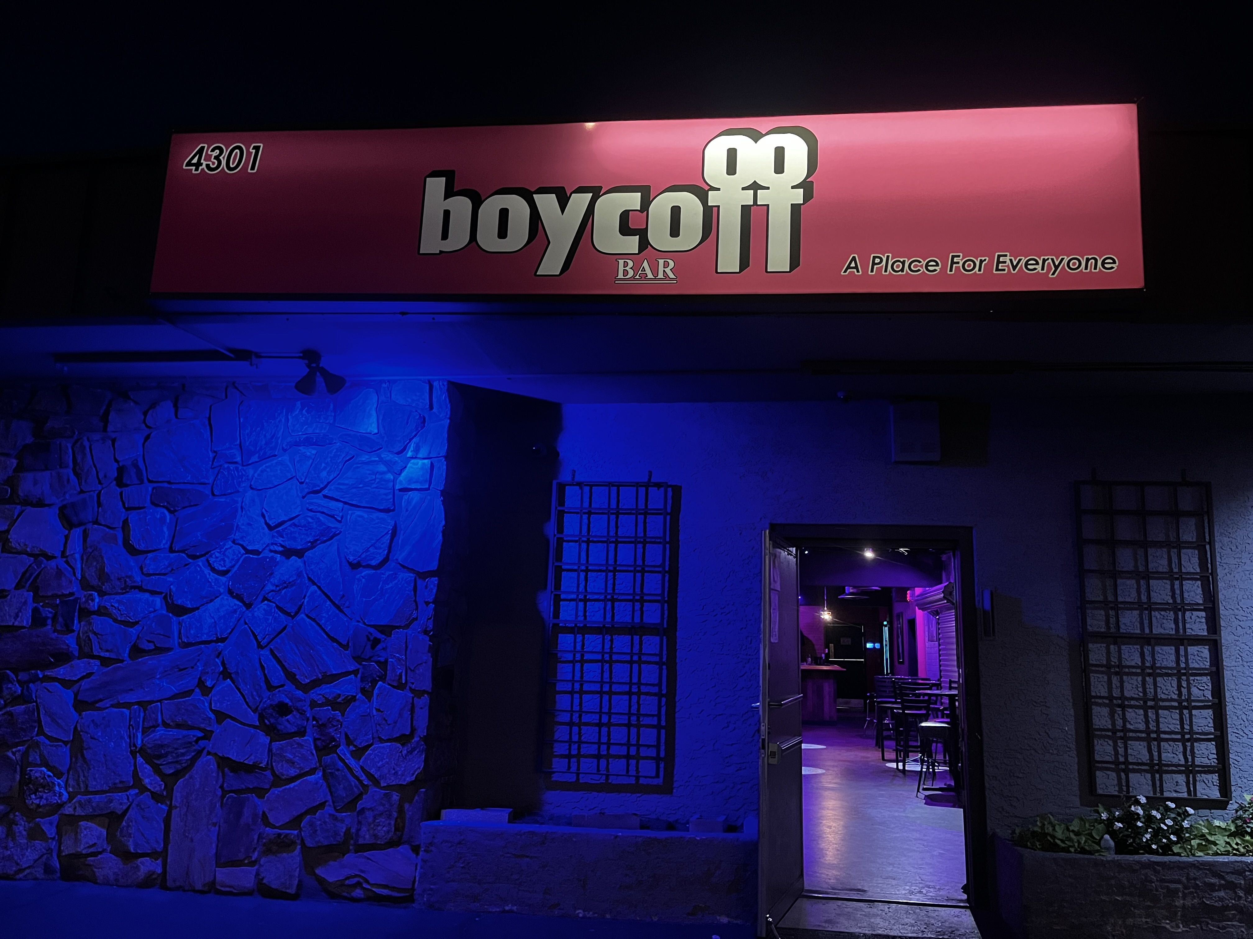 Boycott Bar's pink signs and lights surround an open doorway with more pink lights beckoning inside.
