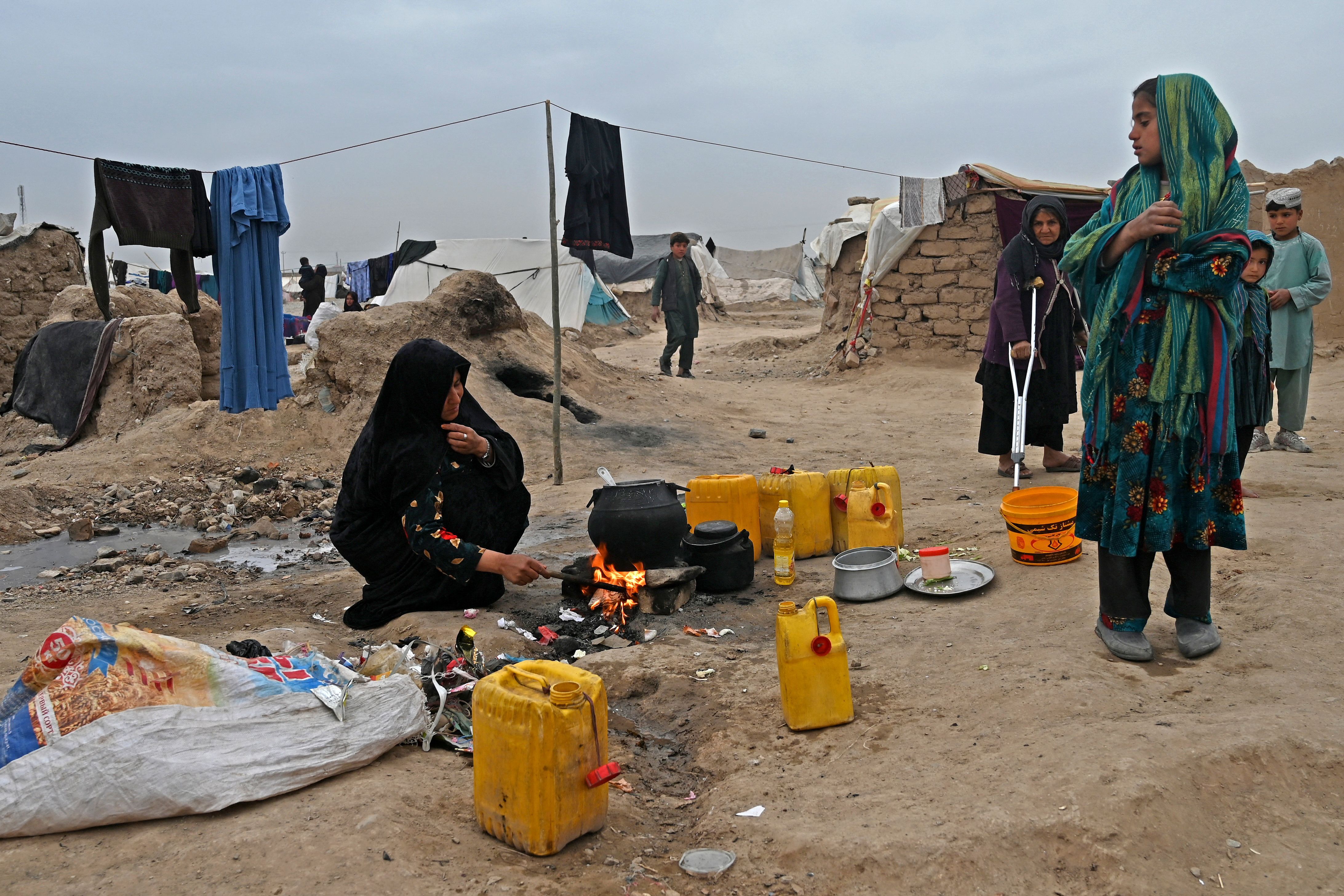 n Une femme déplacée afghane cuisine devant sa tente au camp de réfugiés de Shaidayee dans le district d'Injil de la province de Herat le 20 février 2022. 