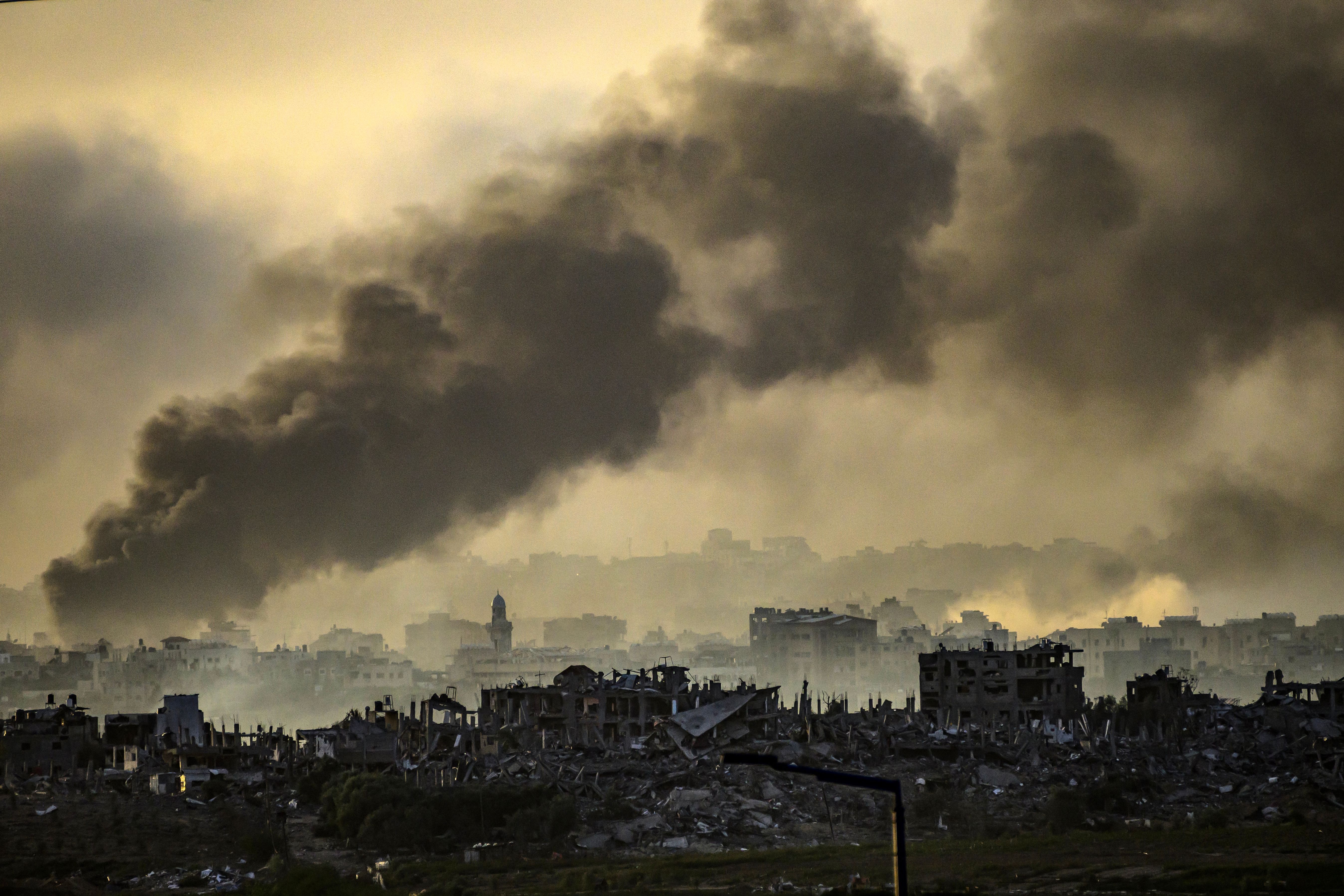 A landscape view of the Gaza Strip showing smoke rising above destroyed buildings. 