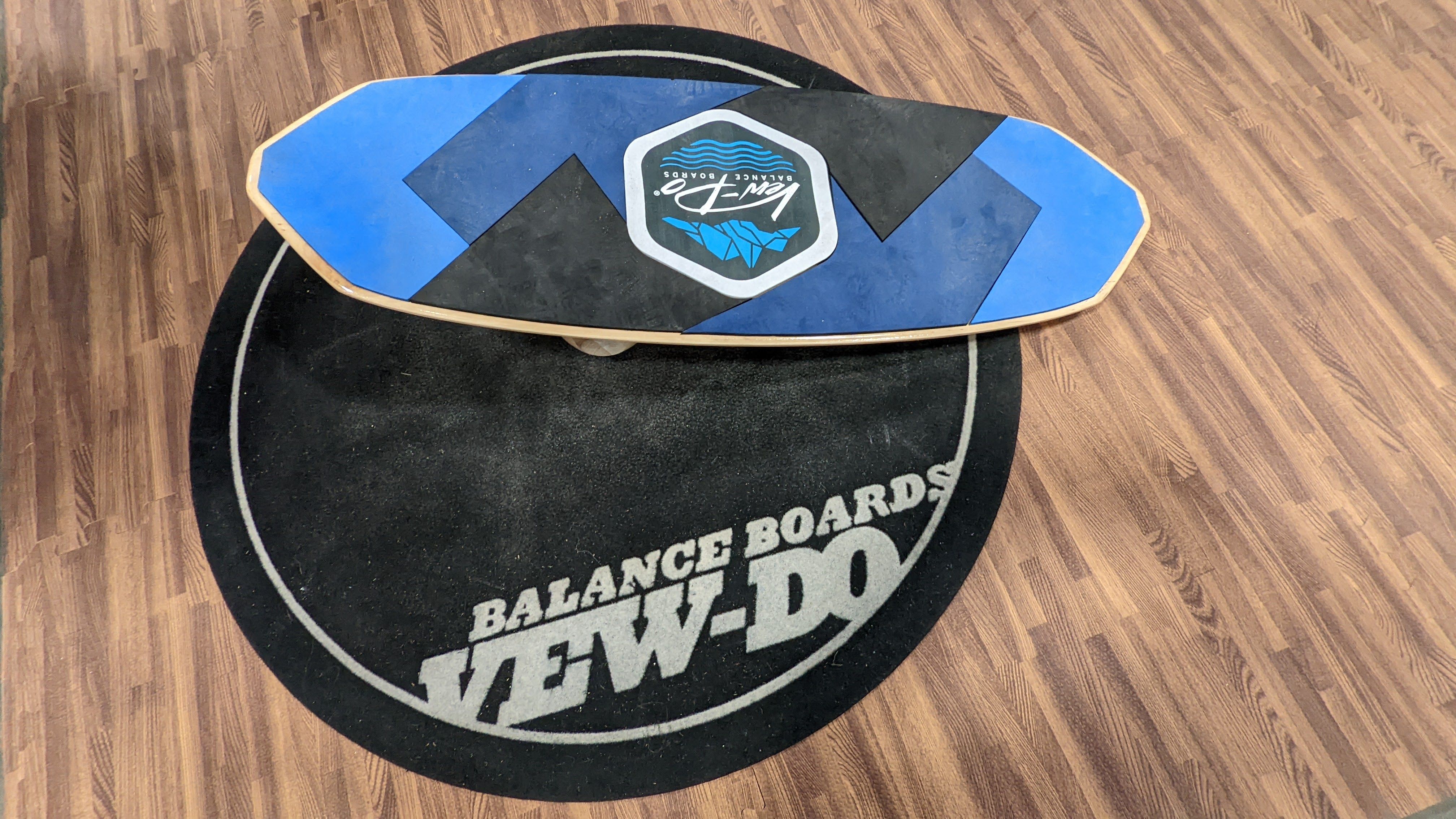 A blue board rests on a practice mat that says "Balance Boards Vew-Do"