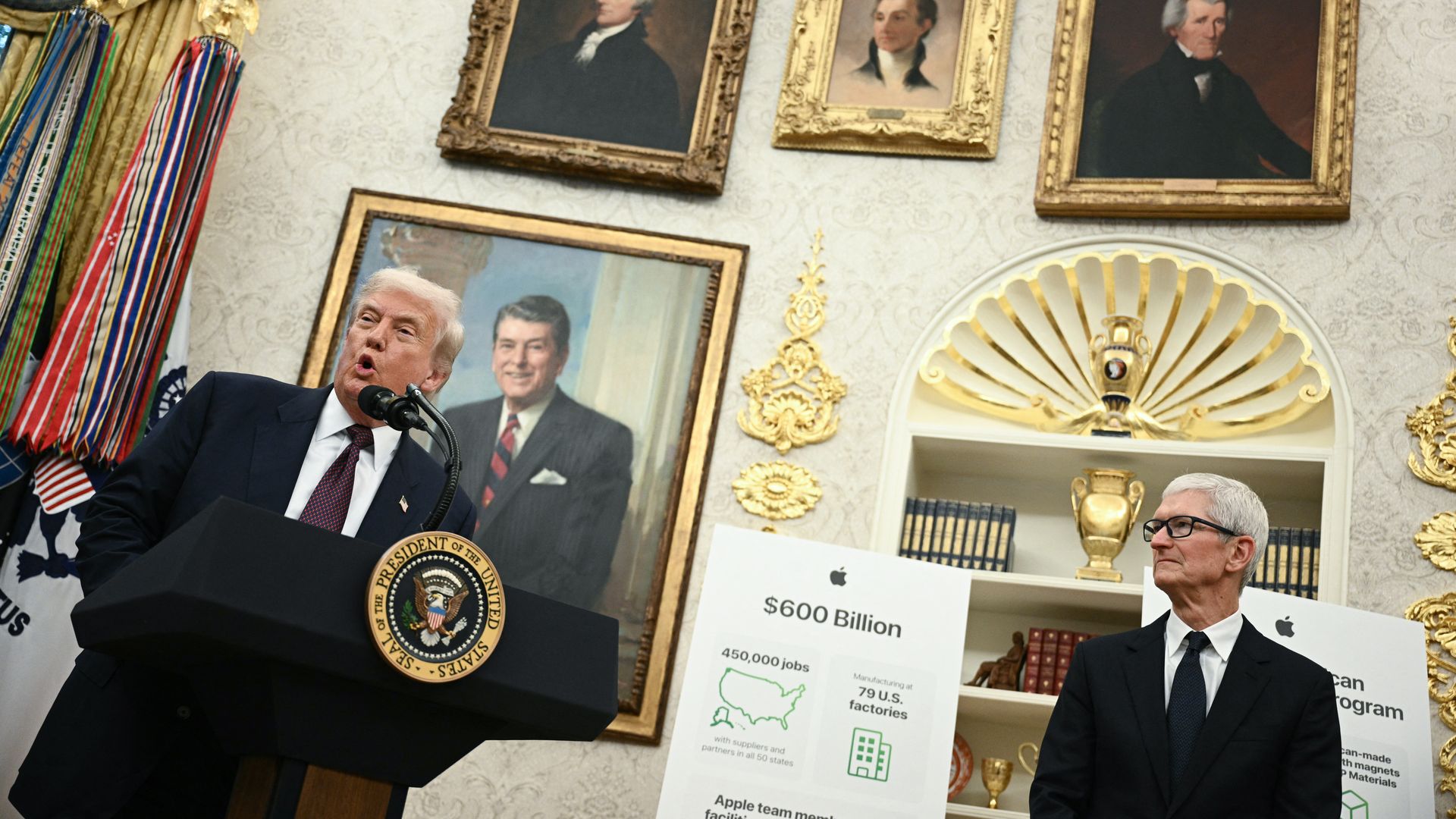 Donald Trump speaking at a podium with the presidential seal, Tim Cook standing nearby, and posters showing Apple investments; in the Oval Office with framed portraits and gold decorations.