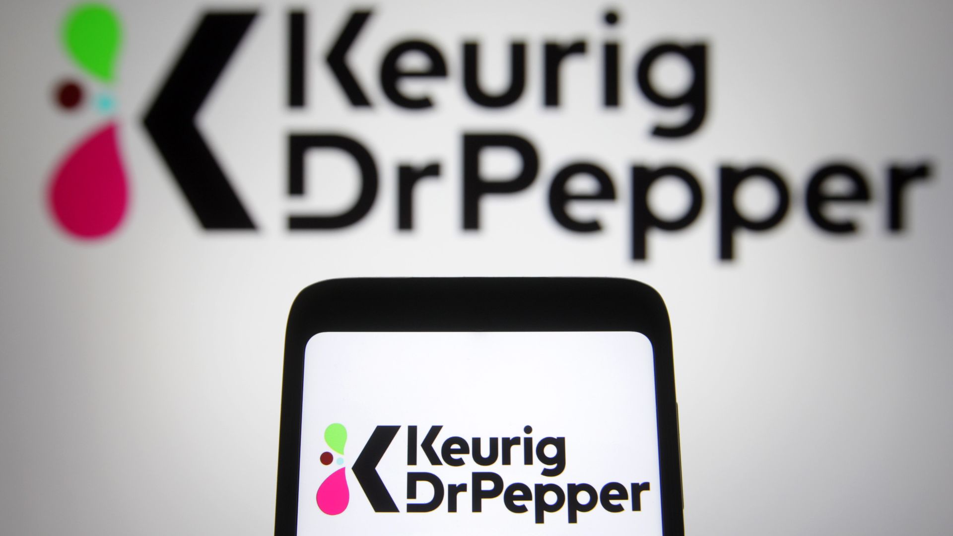 The Keurig Dr. Pepper logo and signage appears above a mobile device featuring the same logo.