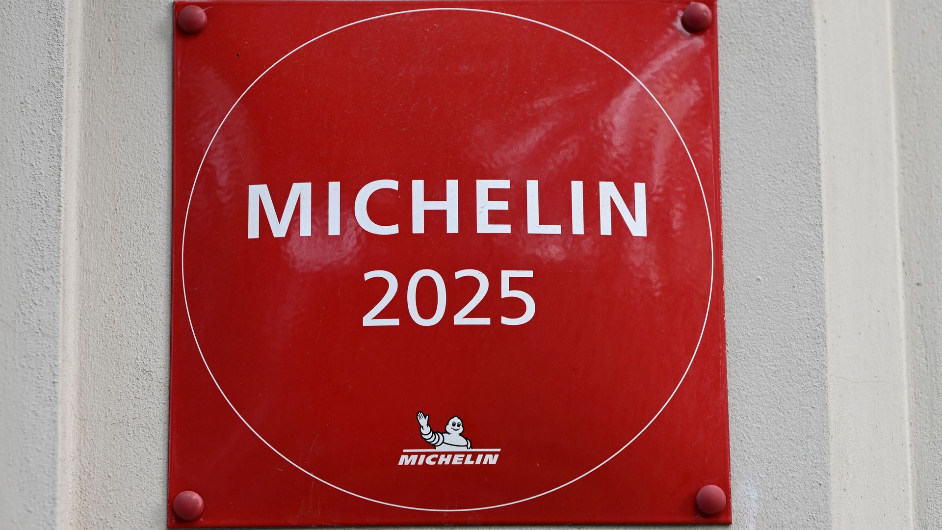 Red Michelin plaque on gray wall with white text "MICHELIN 2025" and small Michelin mascot logo at the bottom center.