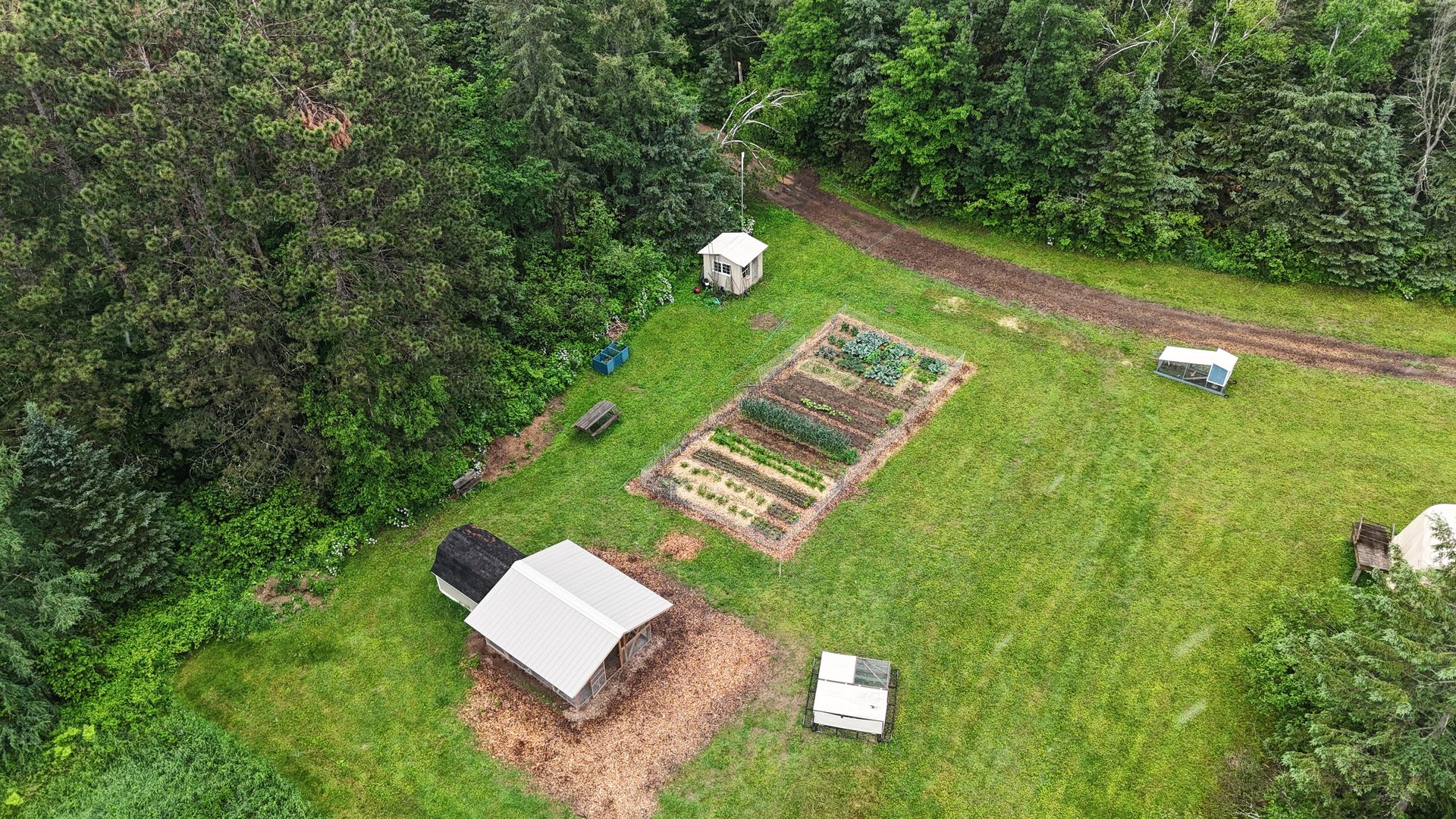 homestead photo taken from above with view of forest and garden