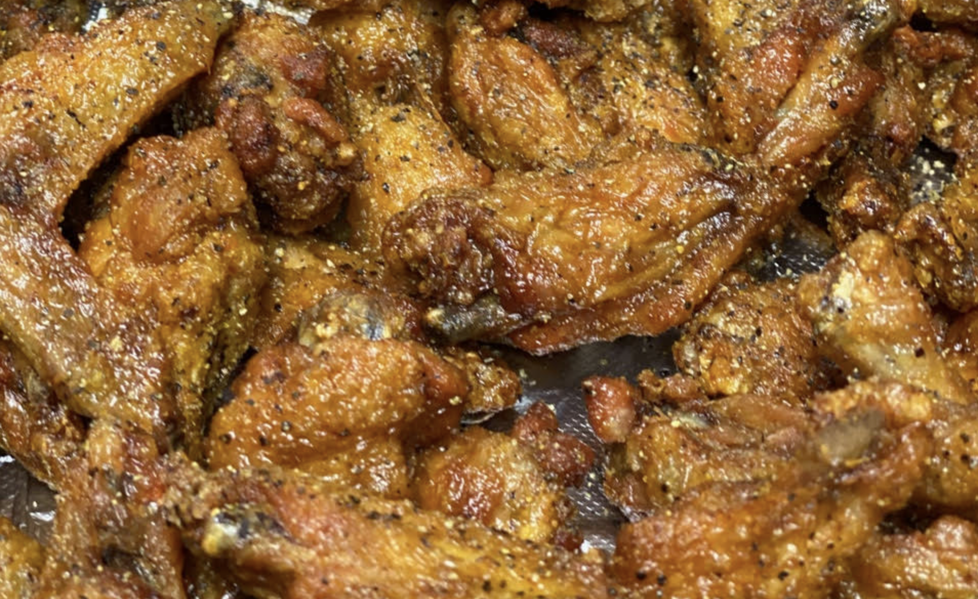A close-up of crispy lemon pepper chicken wings