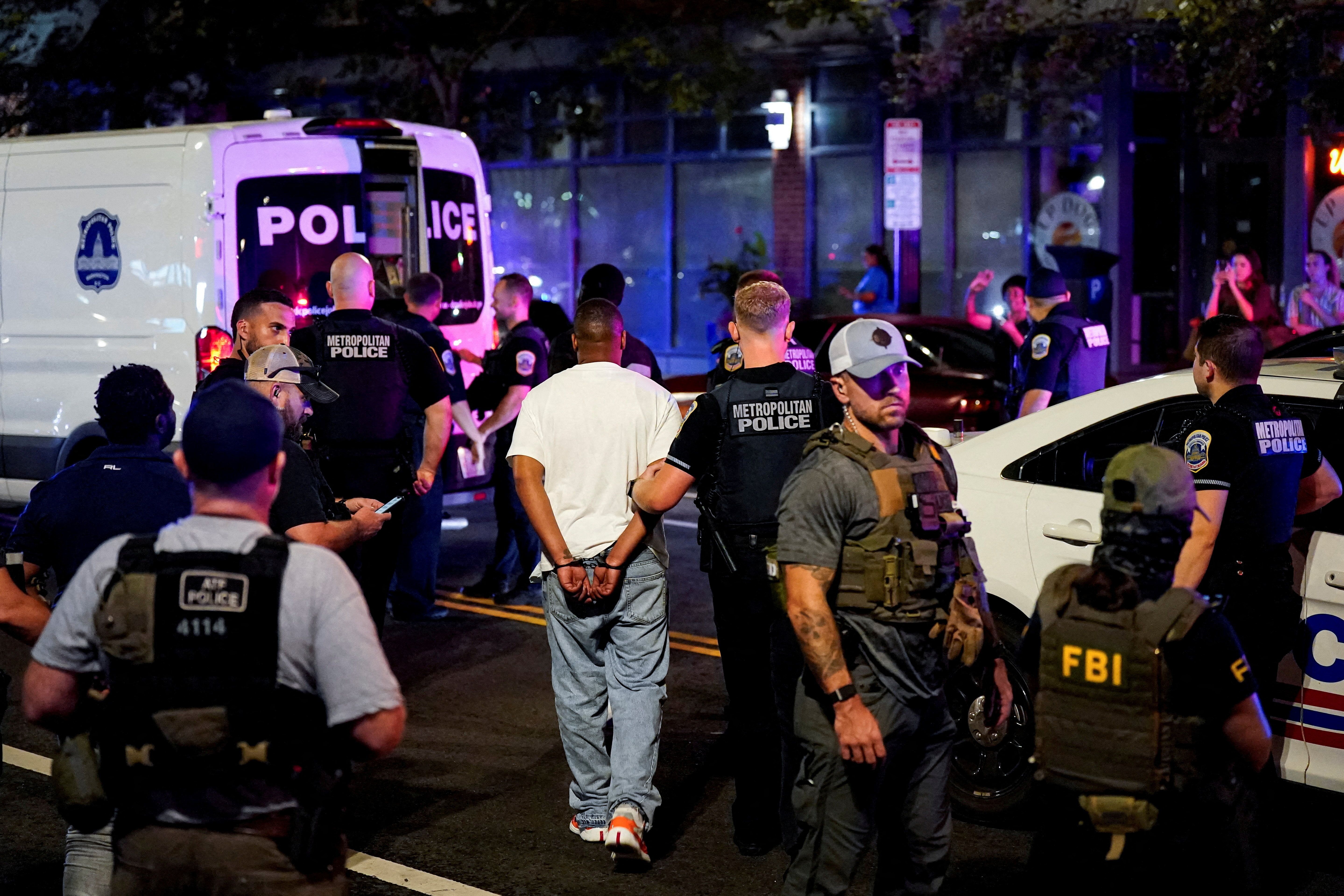 A detained man is led to a Metropolitan Police Department transport vehicle during a traffic stop in D.C. on Sunday.