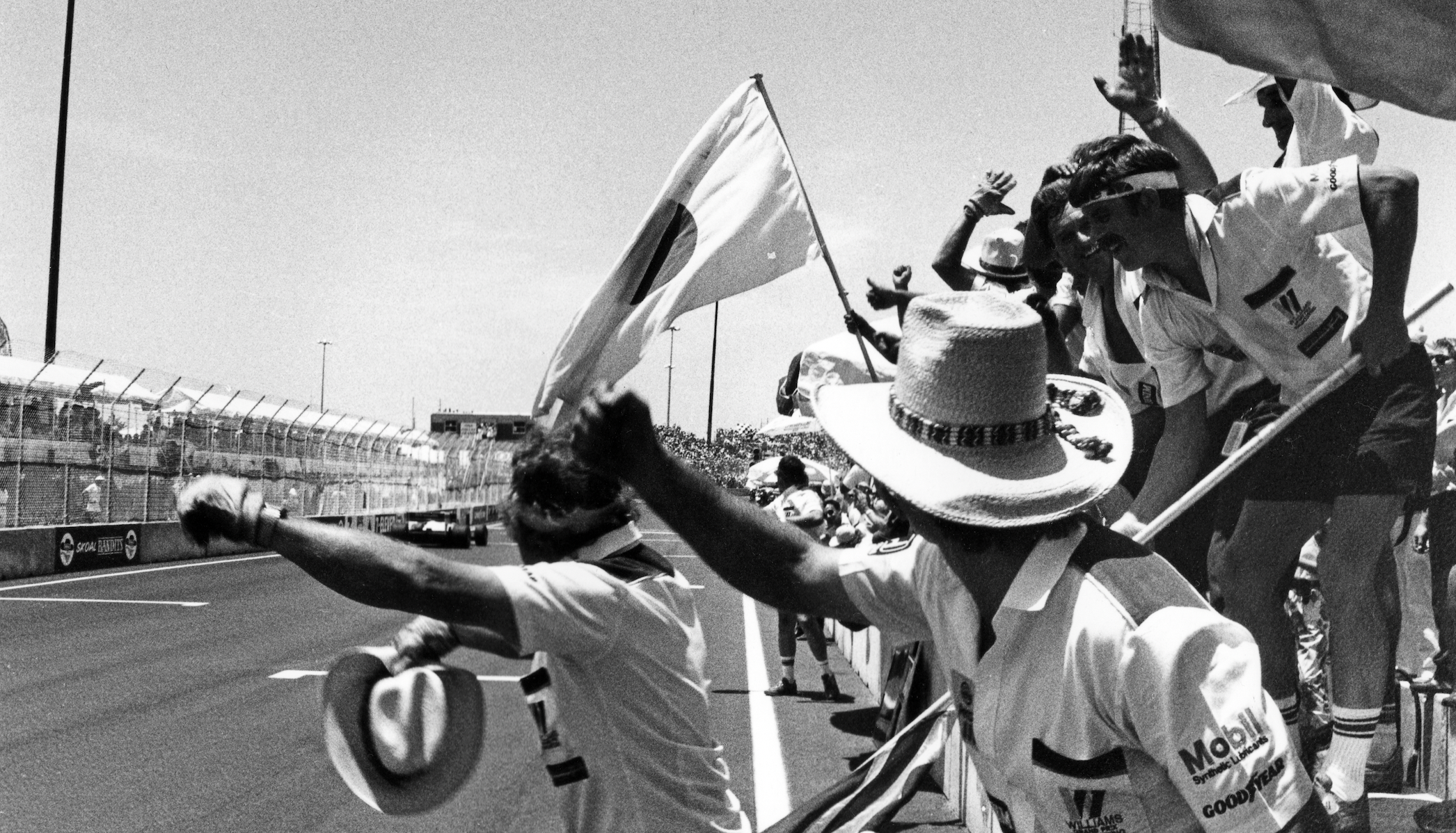 Black and white photo of fans cheering at a car race