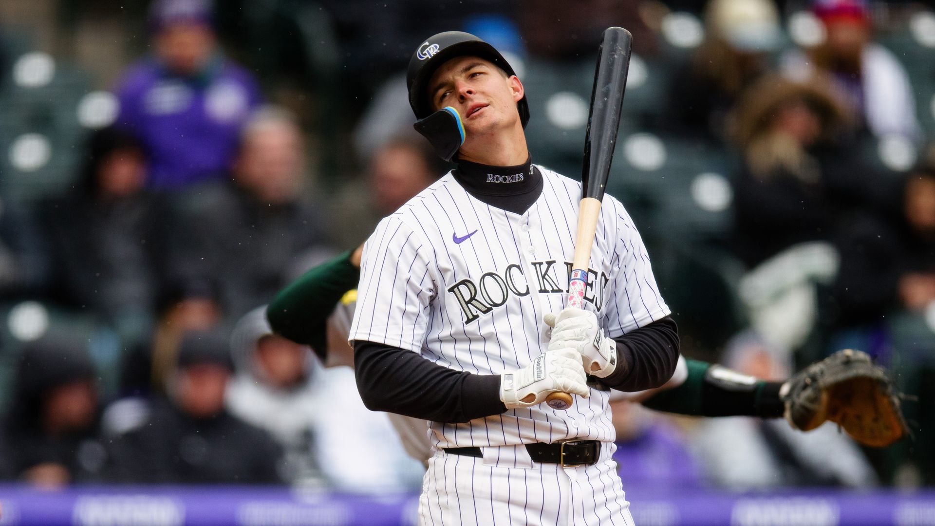 A man holds a baseball bat while looking longingly across.
