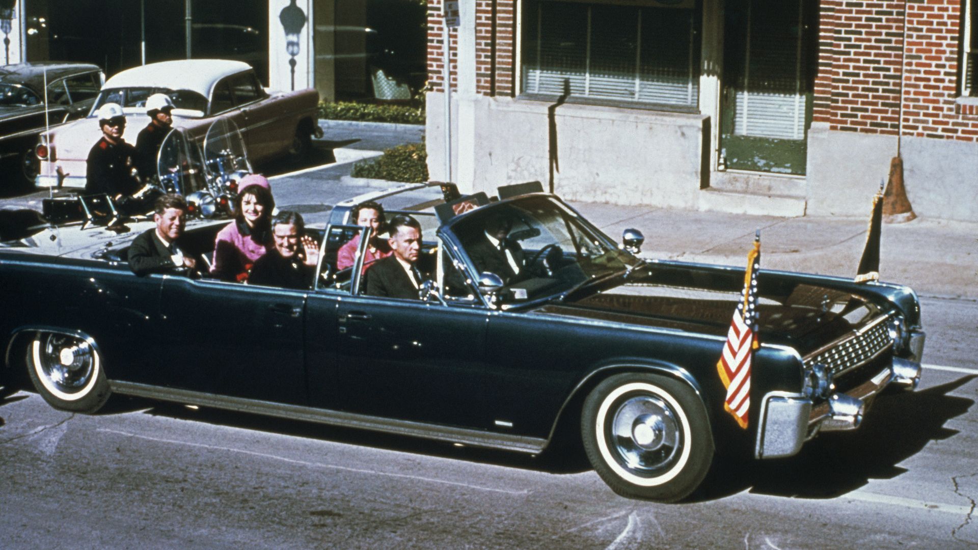 President John F Kennedy, First Lady Jacqueline Kennedy, Texas Governor John Connally and his wife Nellie Connally ride together in a convertible limousine.