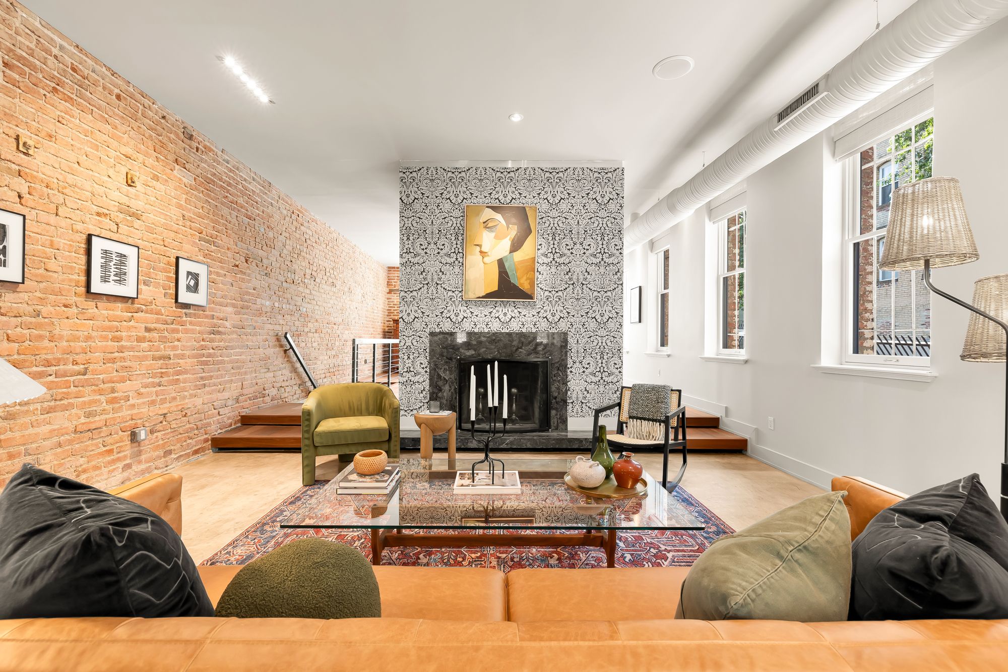 A living room with an exposed brick wall and a patterned fireplace.