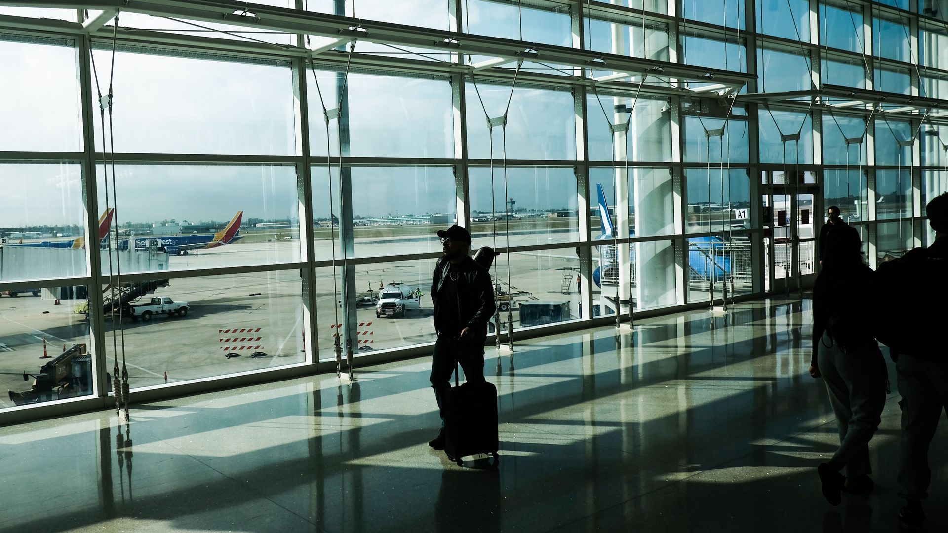 Image shows travelers walking in the New Orleans airport.