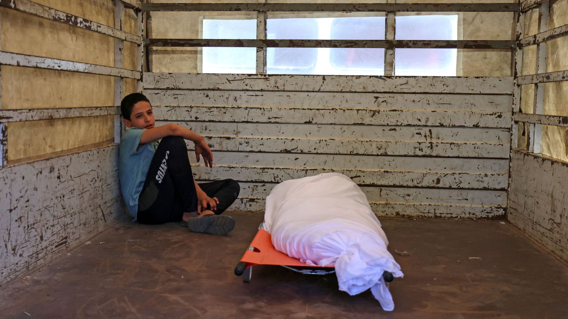 A boy sits with a body after a death in Gaza amid fighting between Israelis and Palestinians.