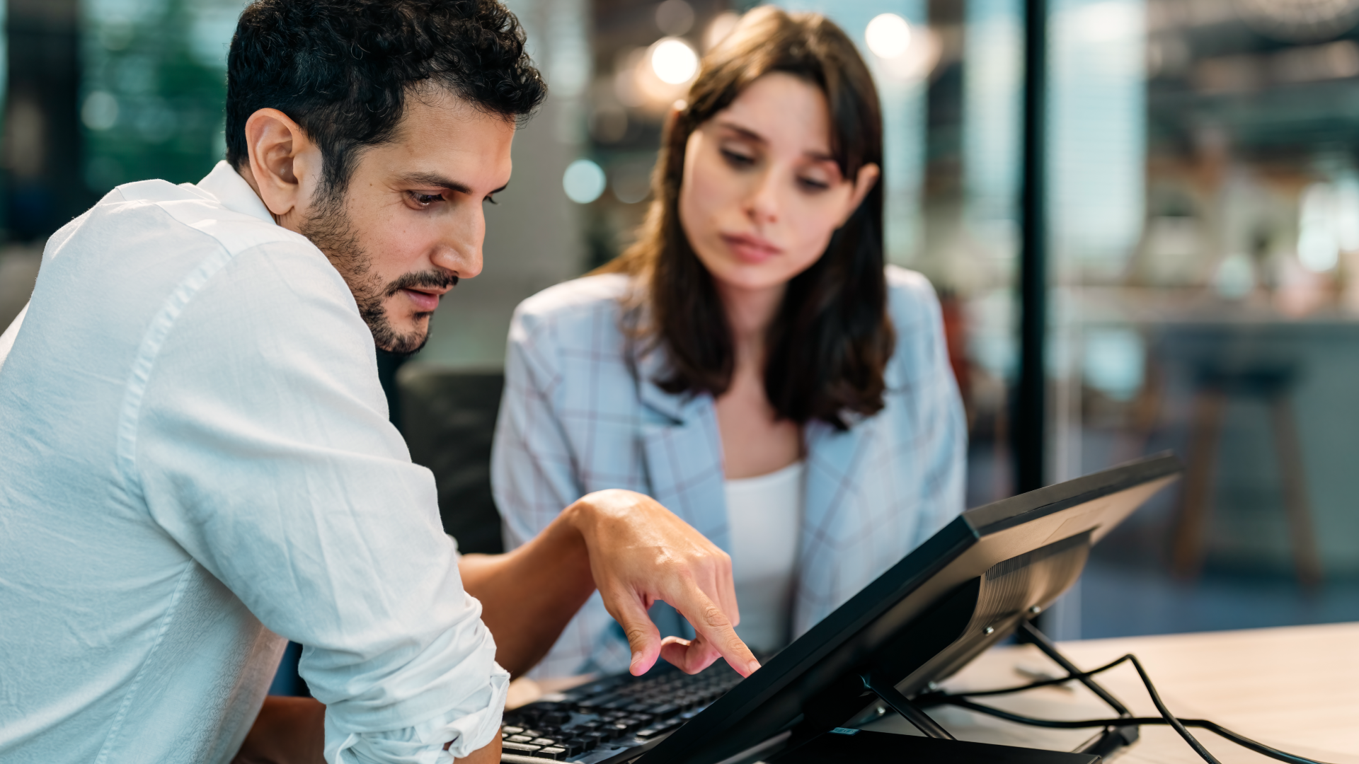 A man and a woman look at a computer screen together.