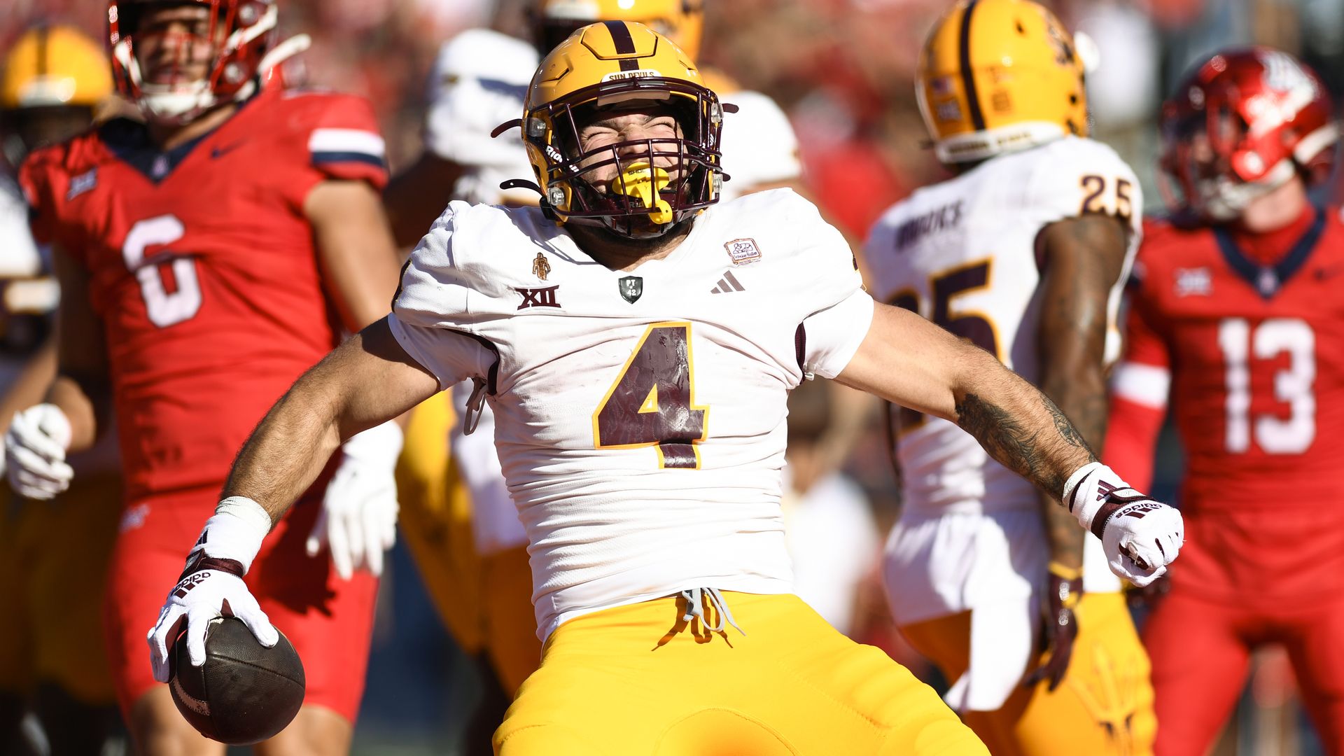 Cam Skattebo celebrates in the end zone while holding the football after scoring a touchdown.