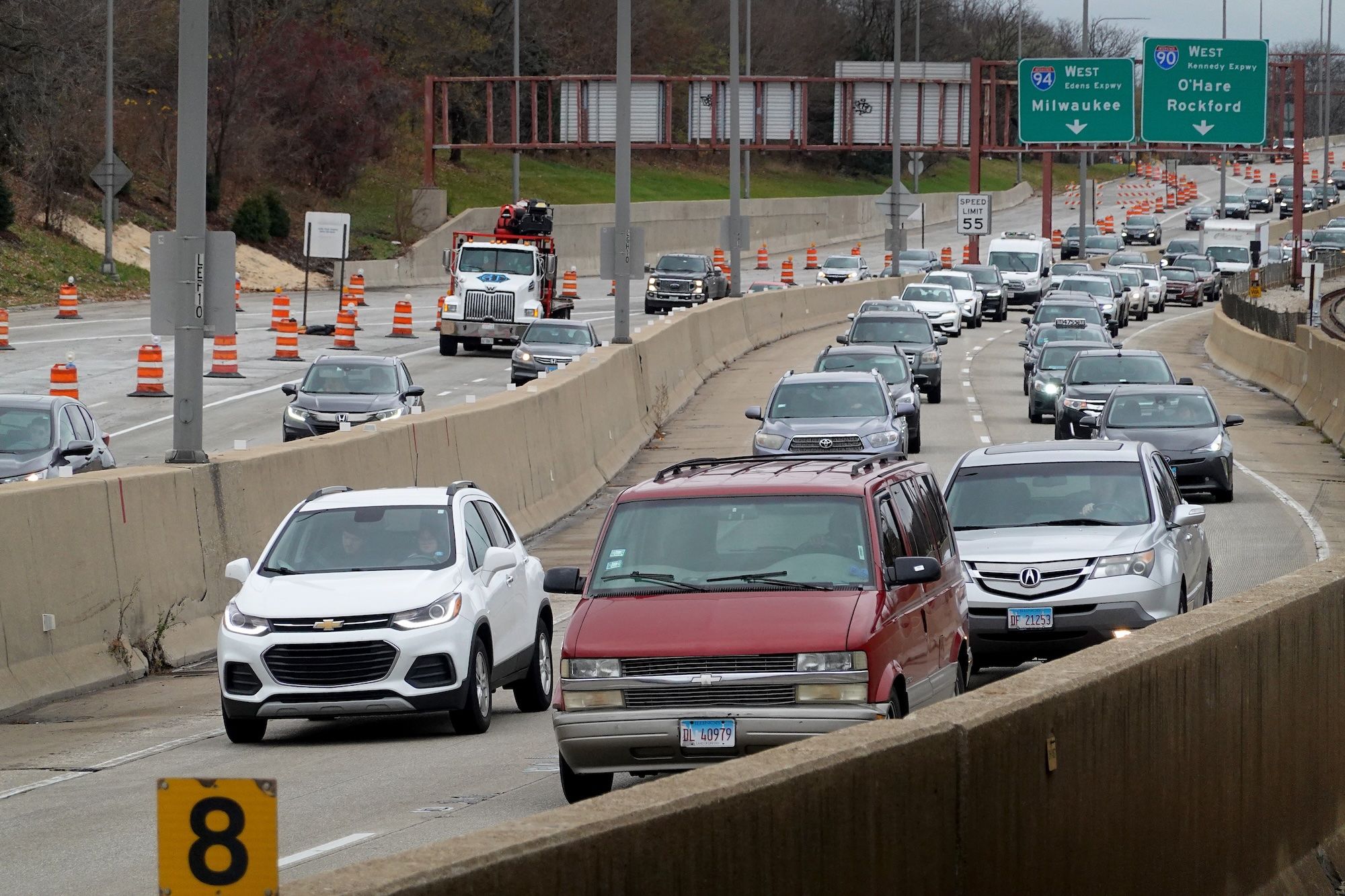 Cars on an expressway with orange cones in the background.
