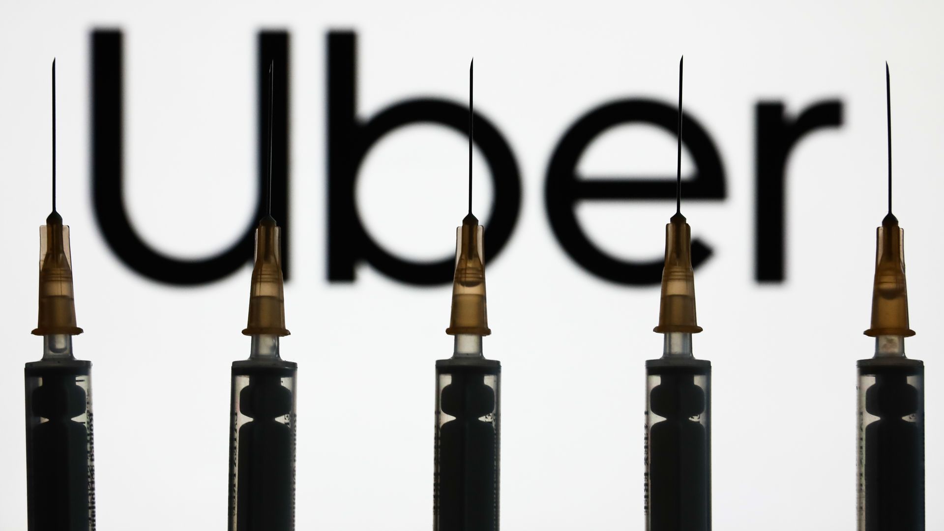 Image of Uber logo behind vaccination needles