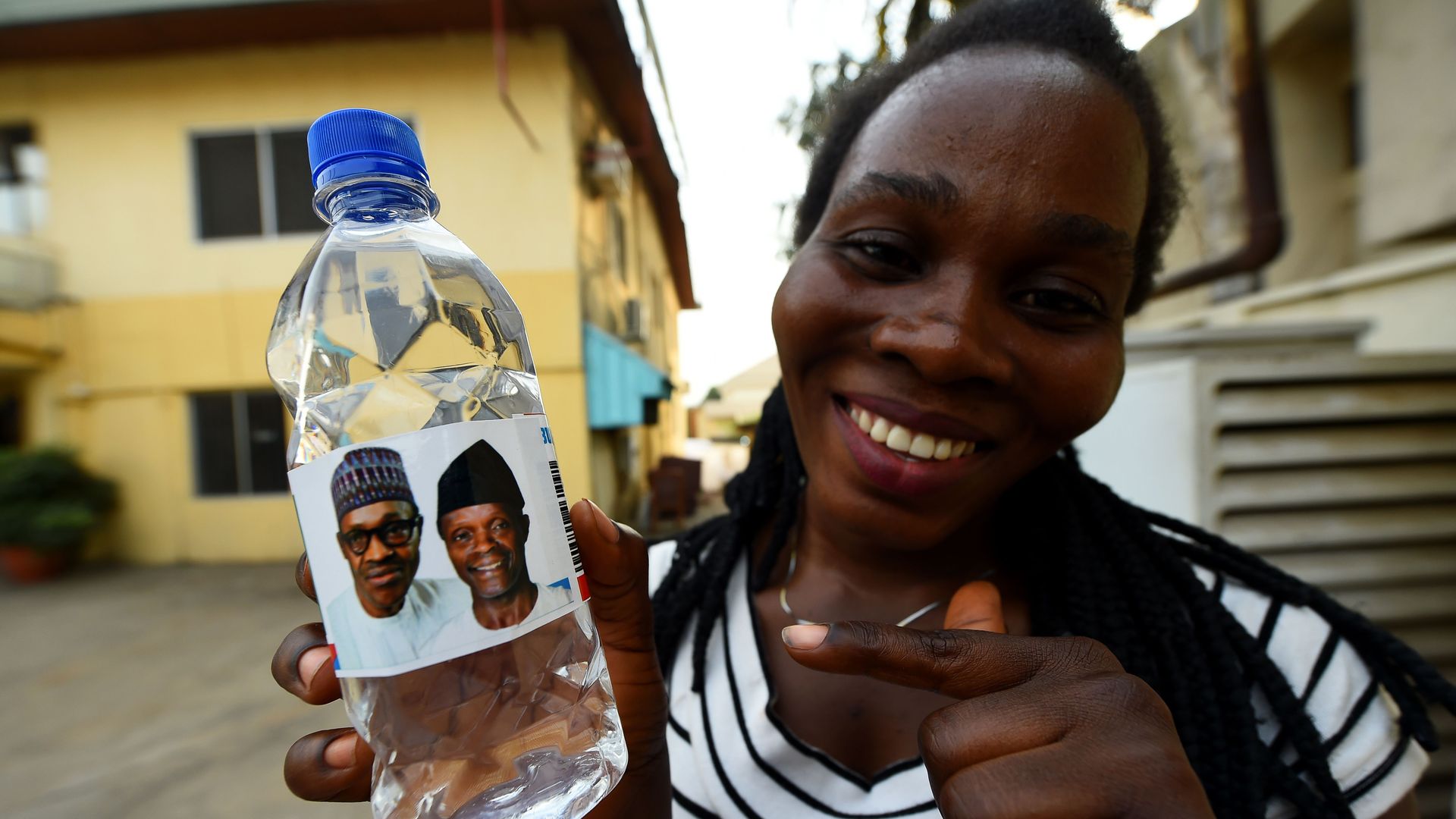 A woman holds a branded table water called Buhari Vendors and bearing photographs of candidates of the ruling All Progressives Congress