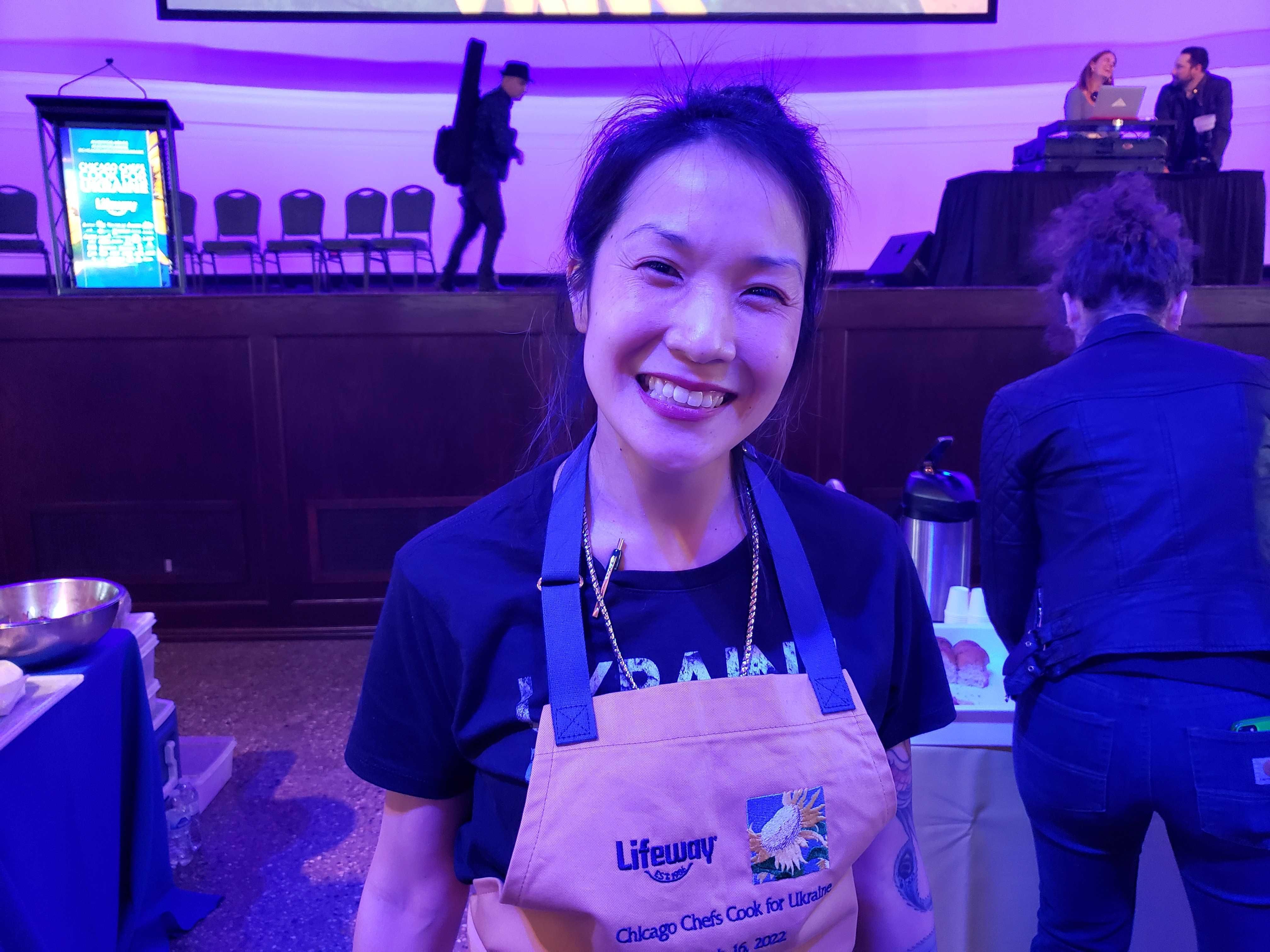 A woman in an apron poses for a photo. 