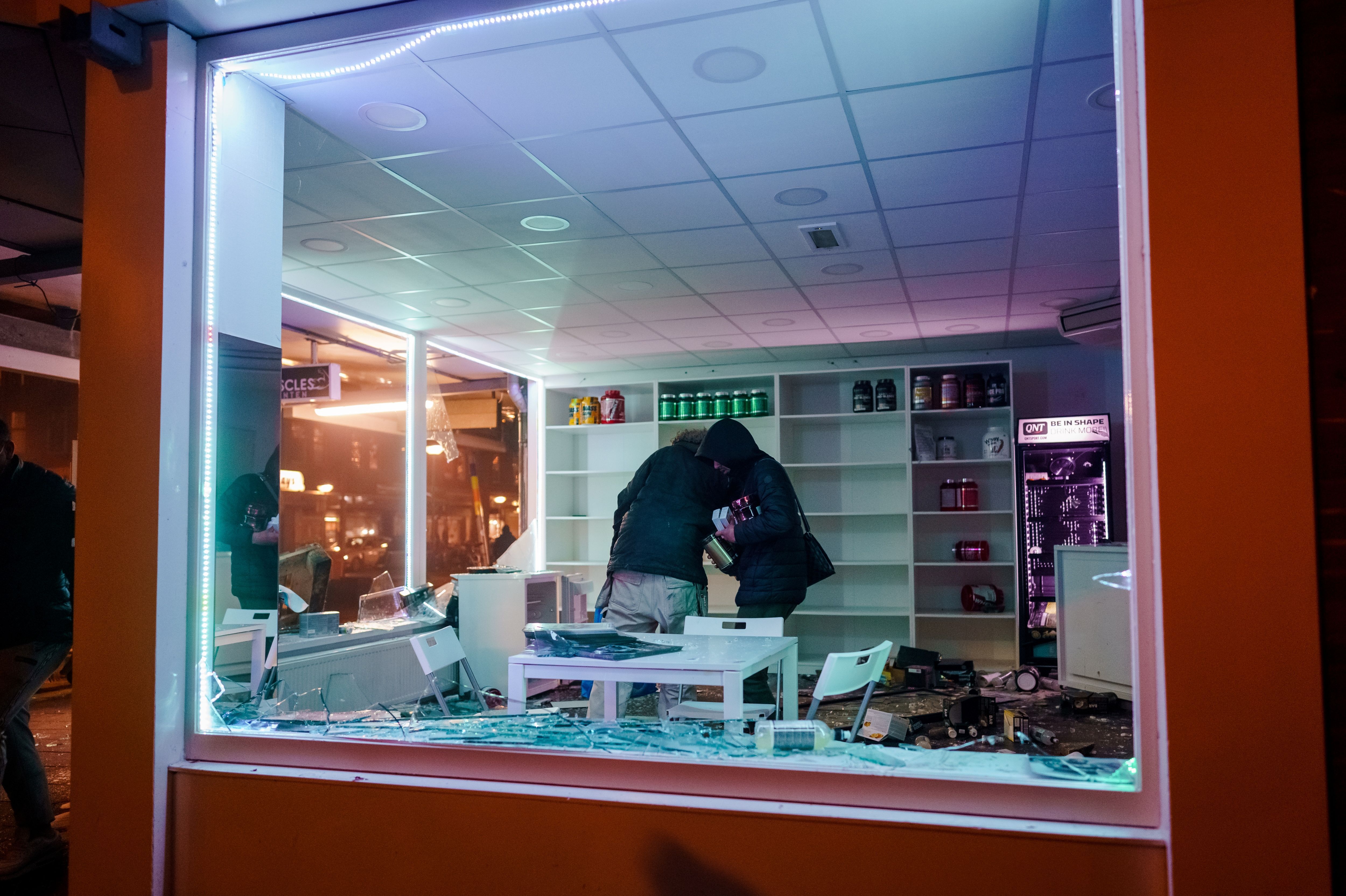 Photo of looters rummaging around in a store with broken windows