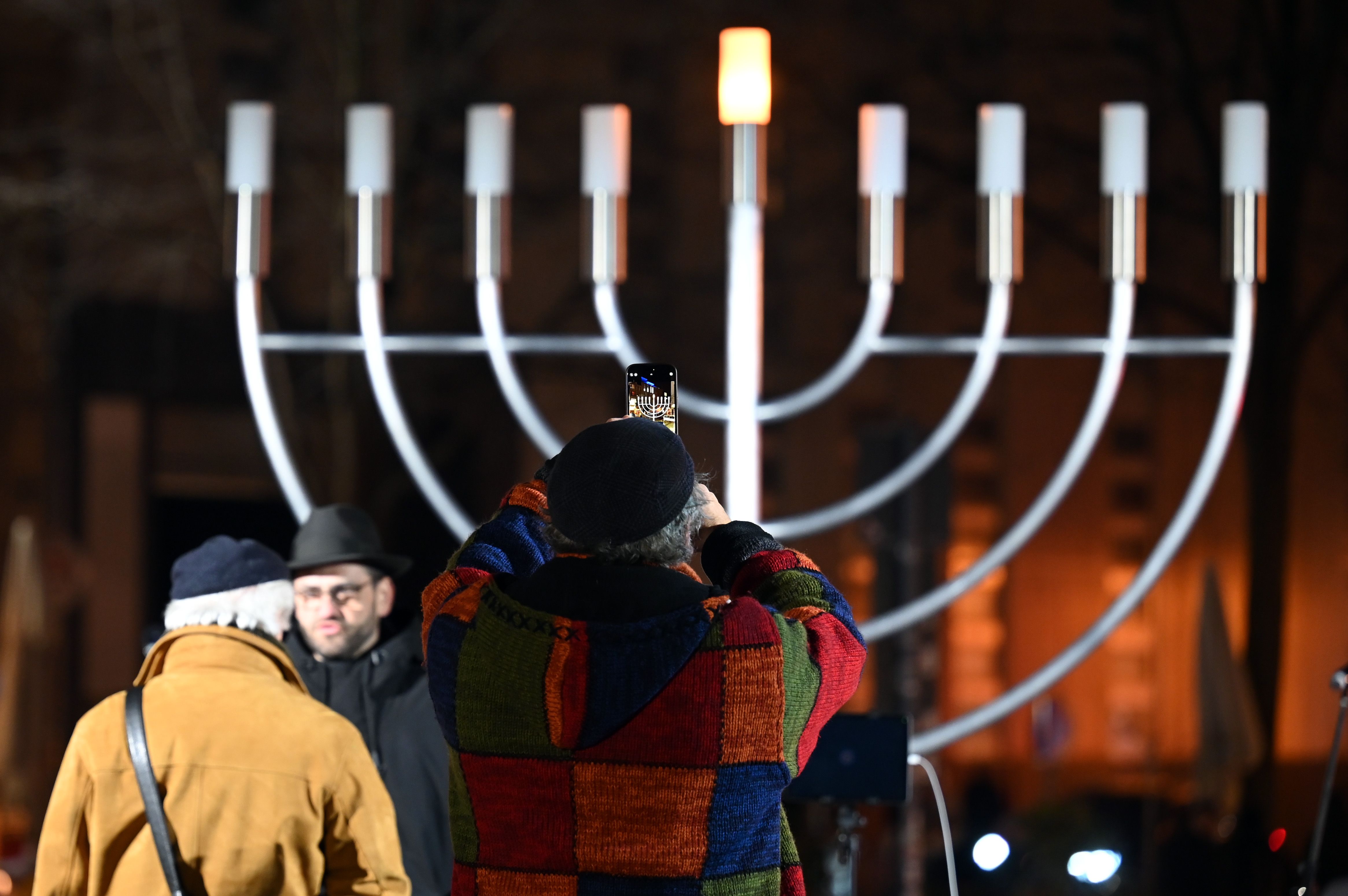 A man photographs the Hanukkah candelabra before the first light is lit in  Leipzig, Germany.