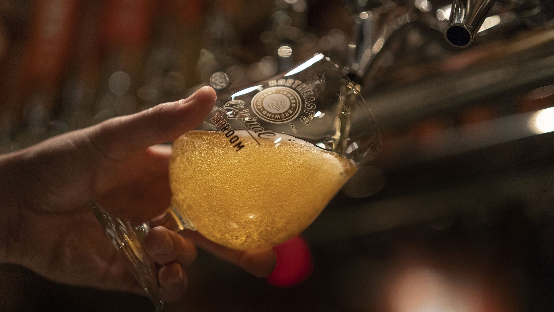 A person pours beer into a glass cup.
