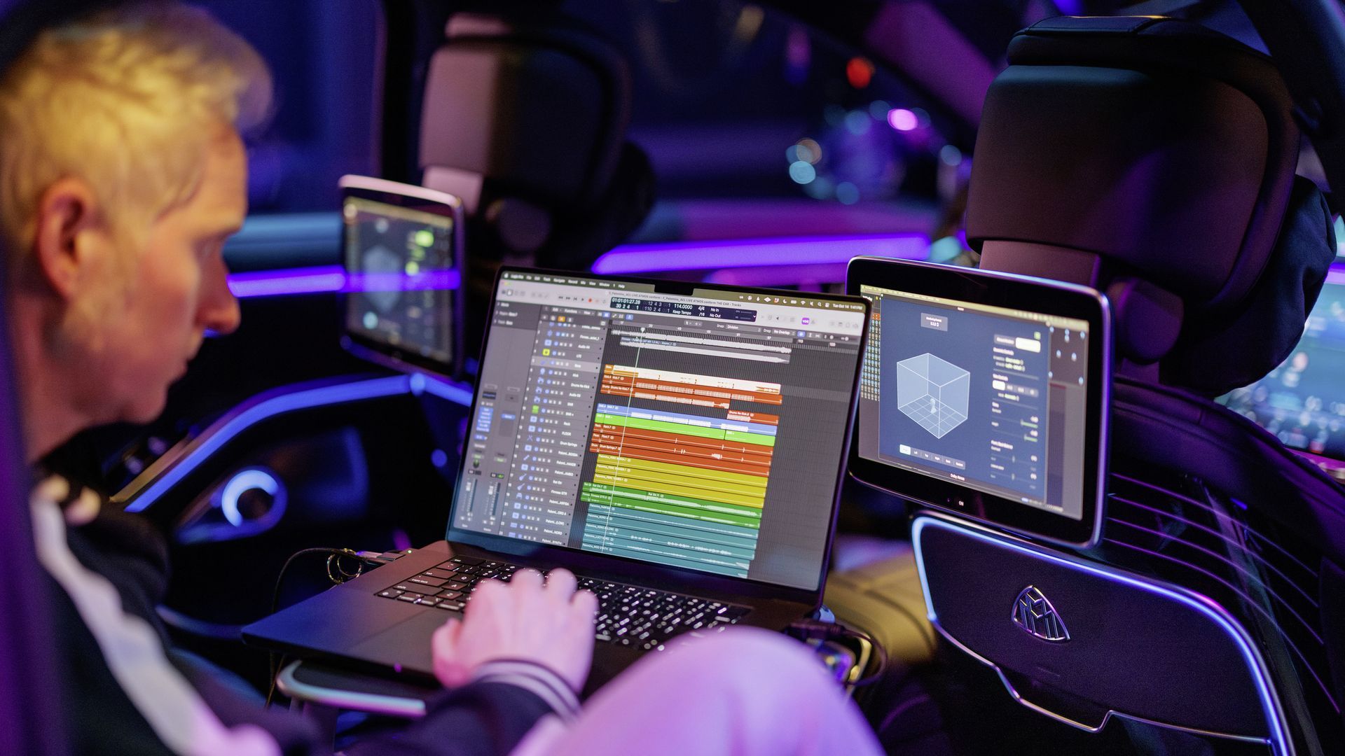 A person types on a laptop inside of a vehicle